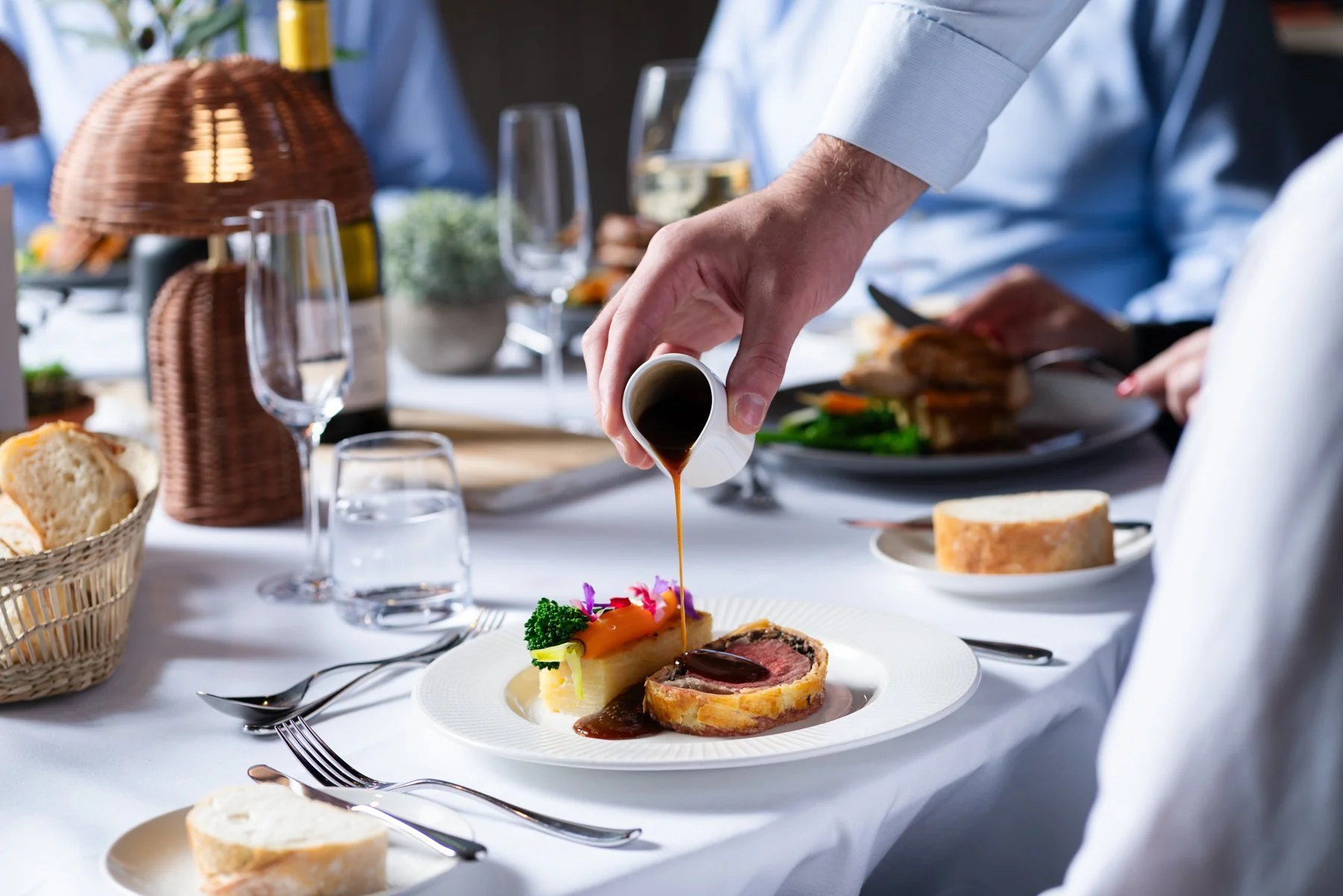 pouring gravy on a beef wellington - spiros caterers