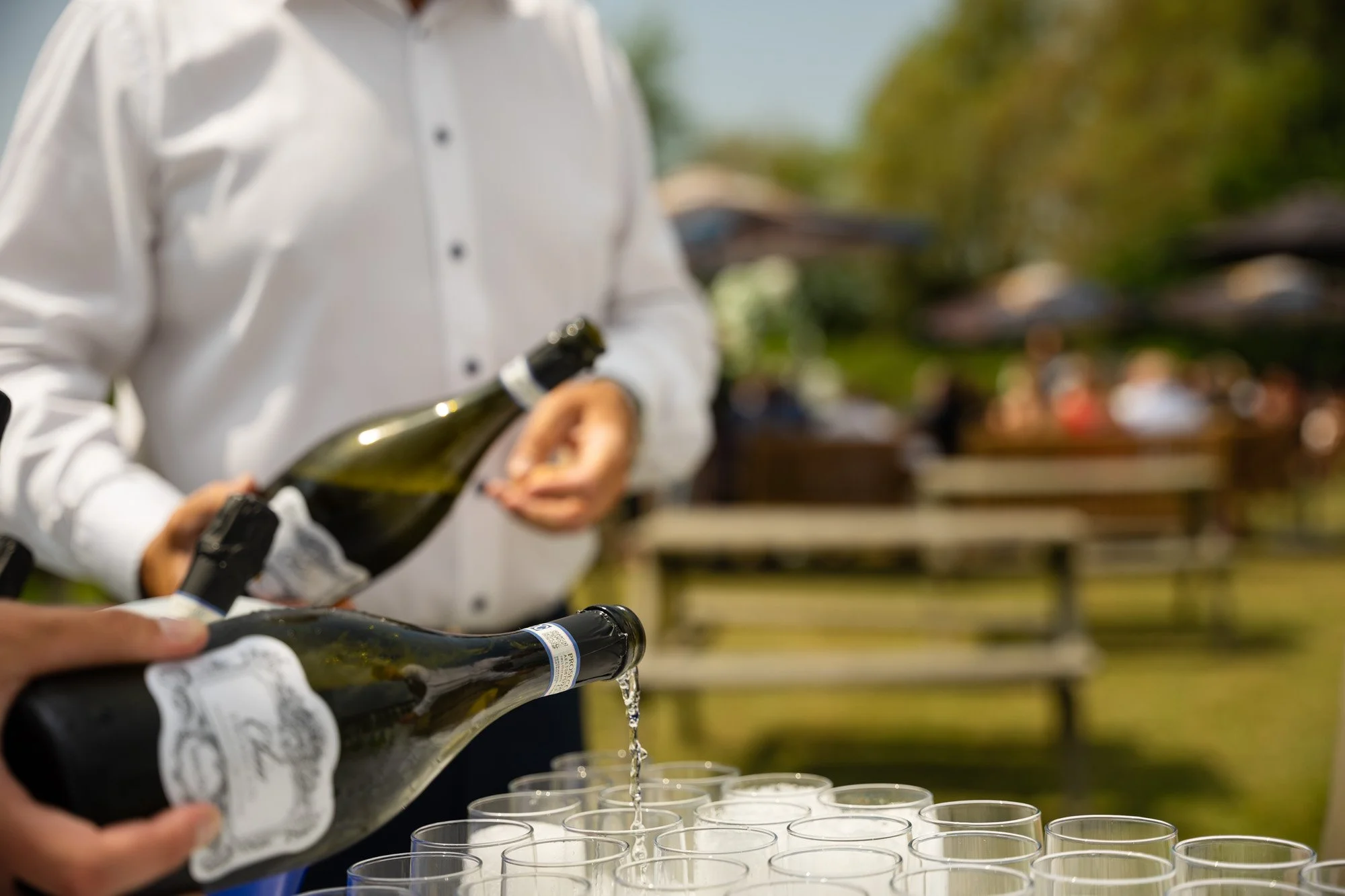 Spiros caterers pouring champagne flutes at a wedding in the sun