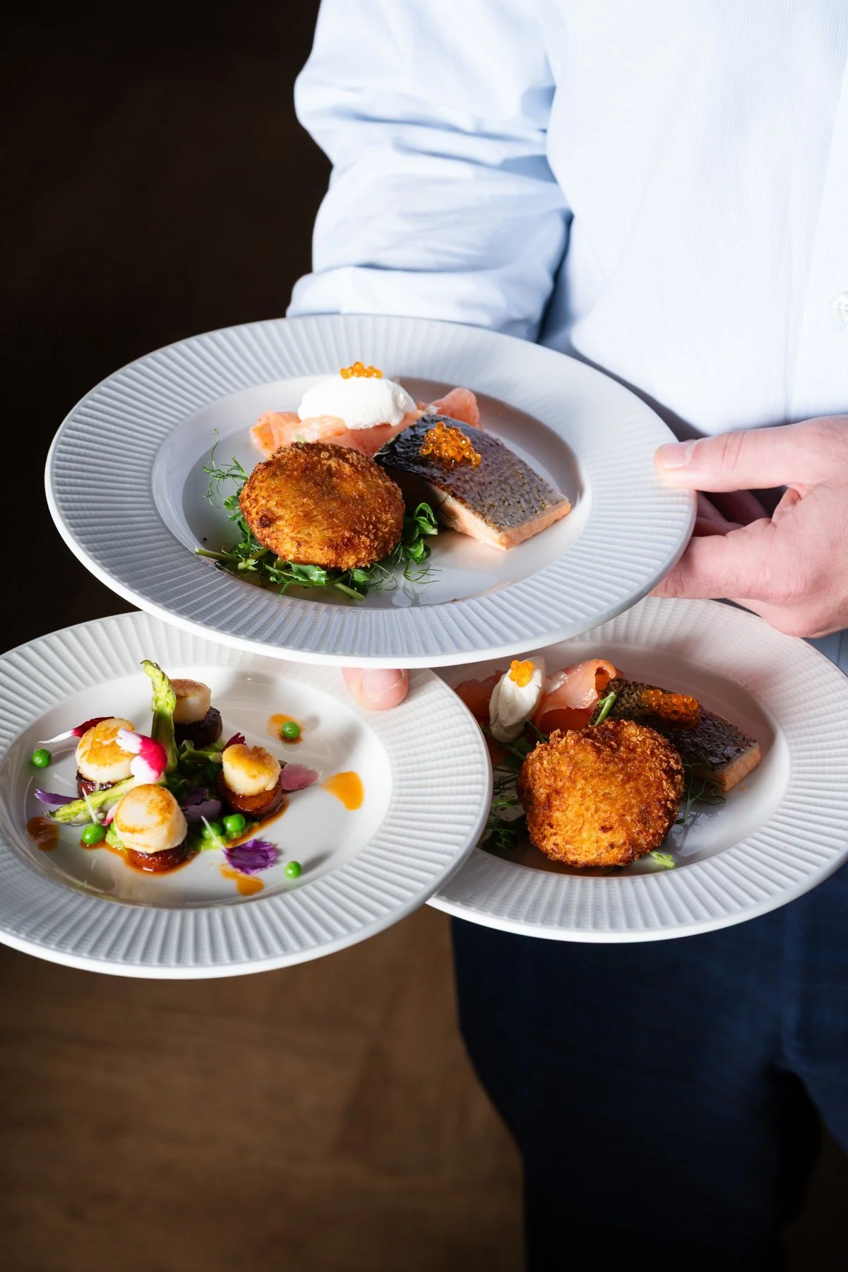 chef holding 3 dishes from spiros