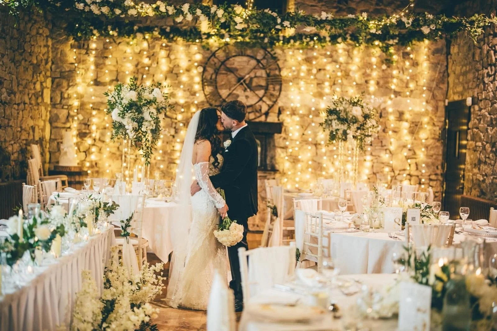 bride and groom kissing in front of fairy lights wall at pencoed house wedding venue