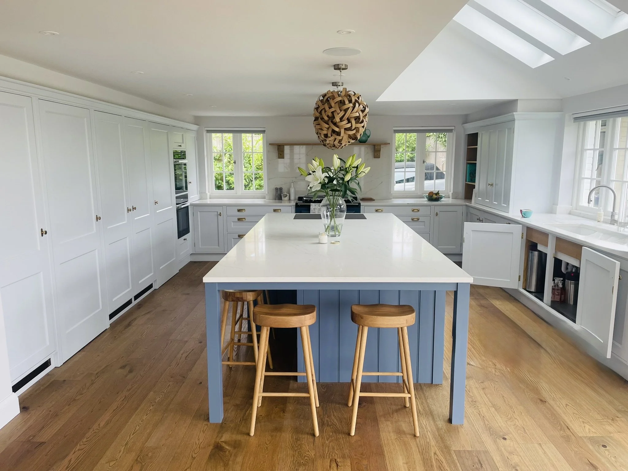 Central kitchen island with seating in a light painted kitchen