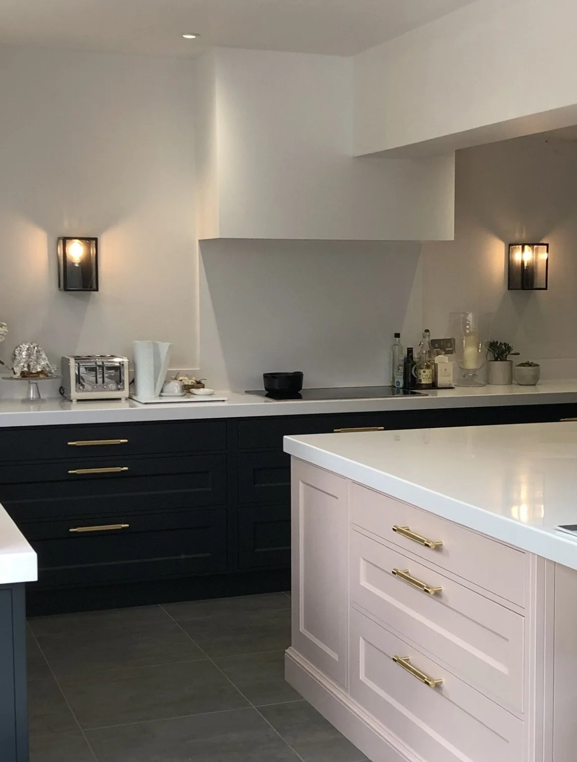 Painted bespoke kitchen island with pale stone worktop and brass handles