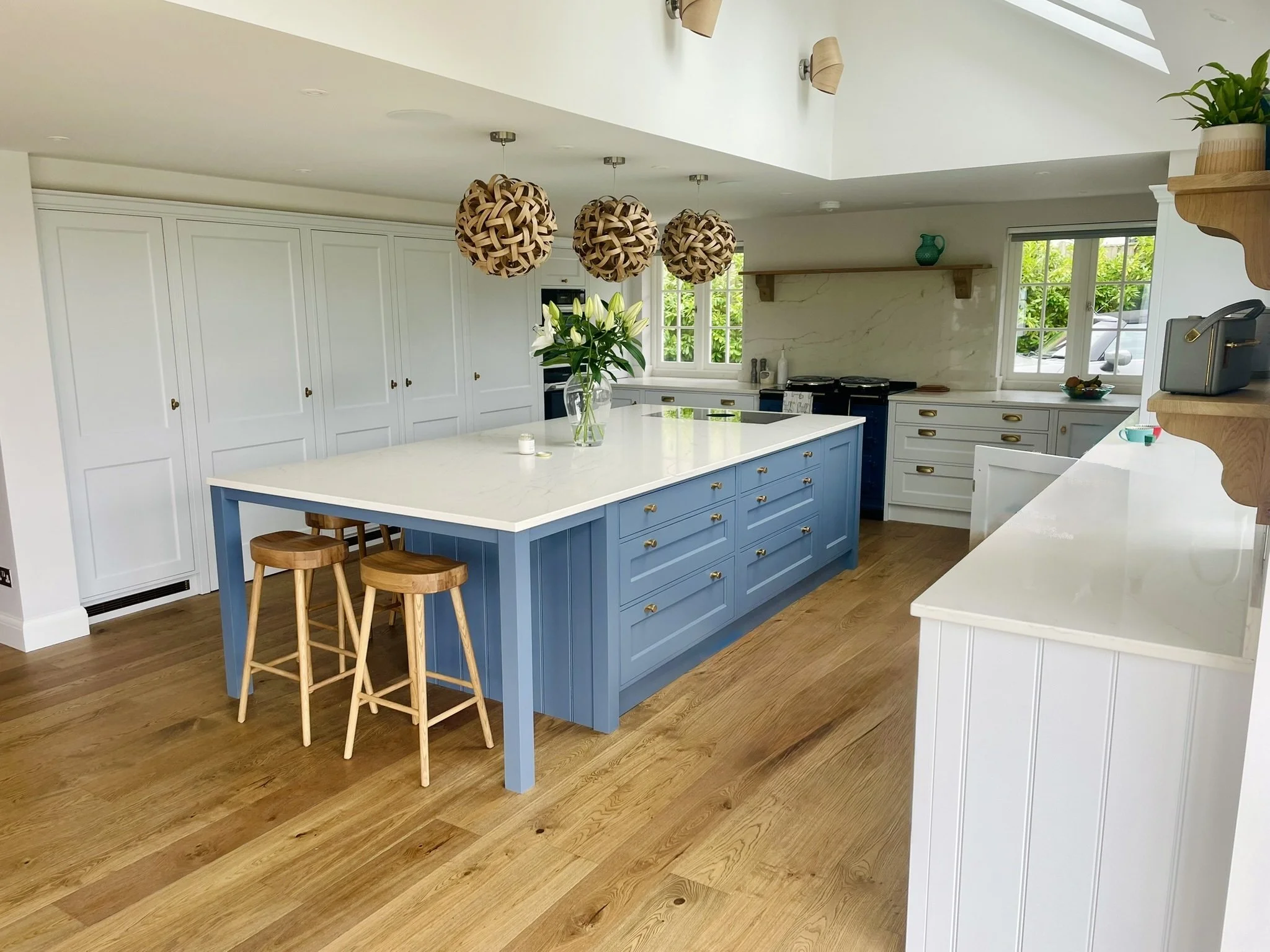 Wide view of a painted kitchen showing the island, cabinetry and surrounding work areas