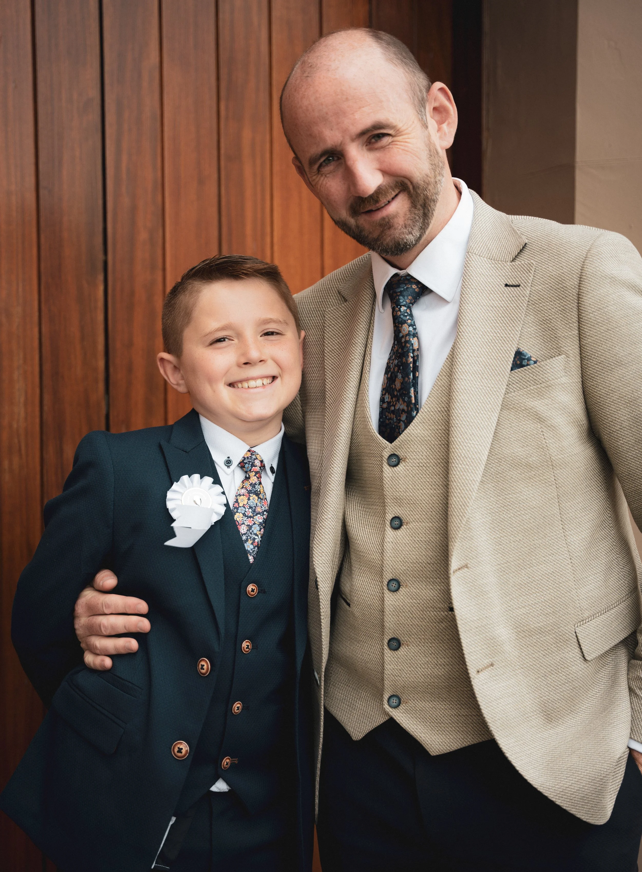 A portrait of a smiling father and boy stand close together after his first communion in Ballyheigue, Co.Kerry