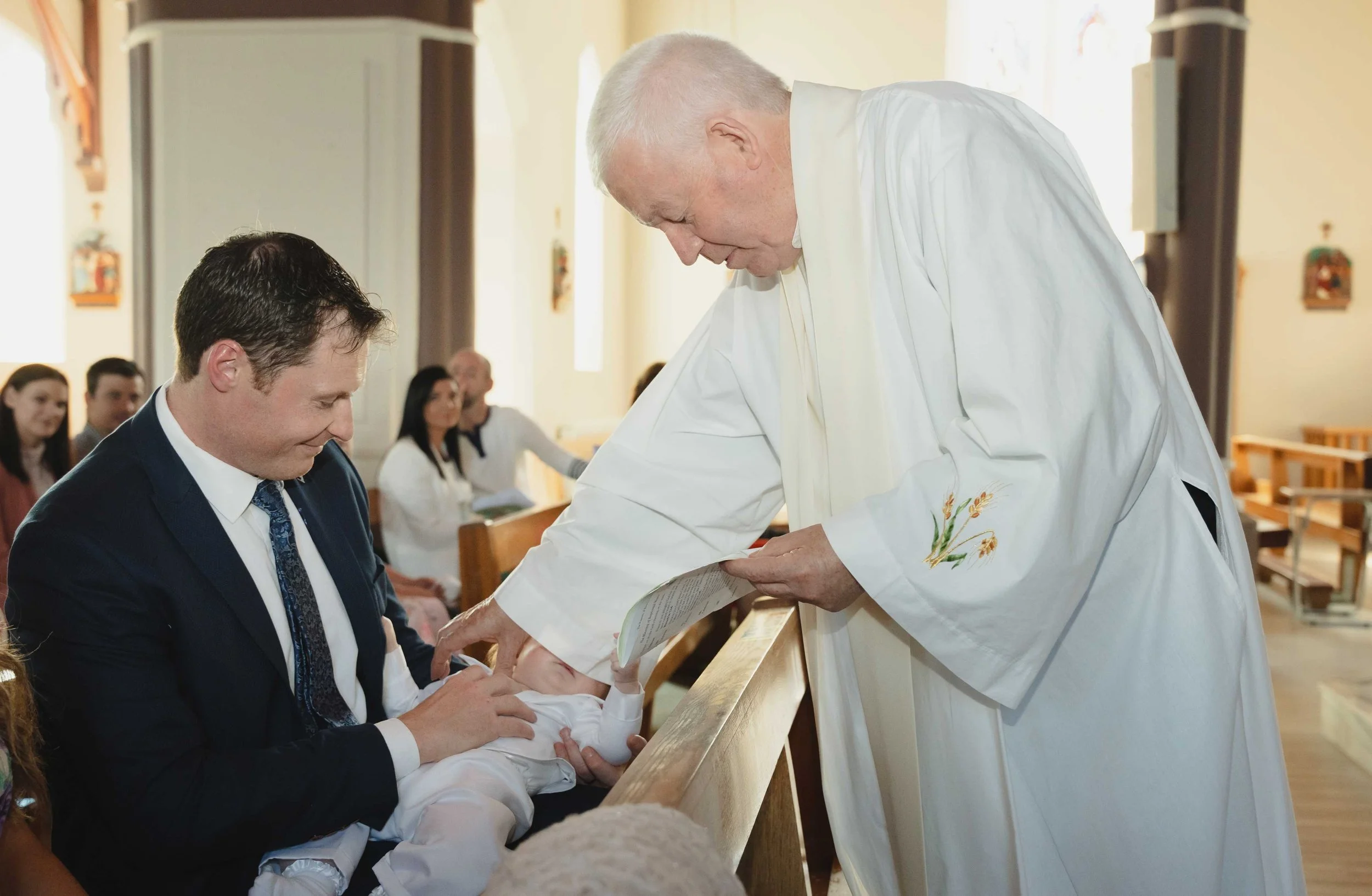 A priest performing a baptism ceremony with a baby in Ballyheigue Church, Co.Kerry.