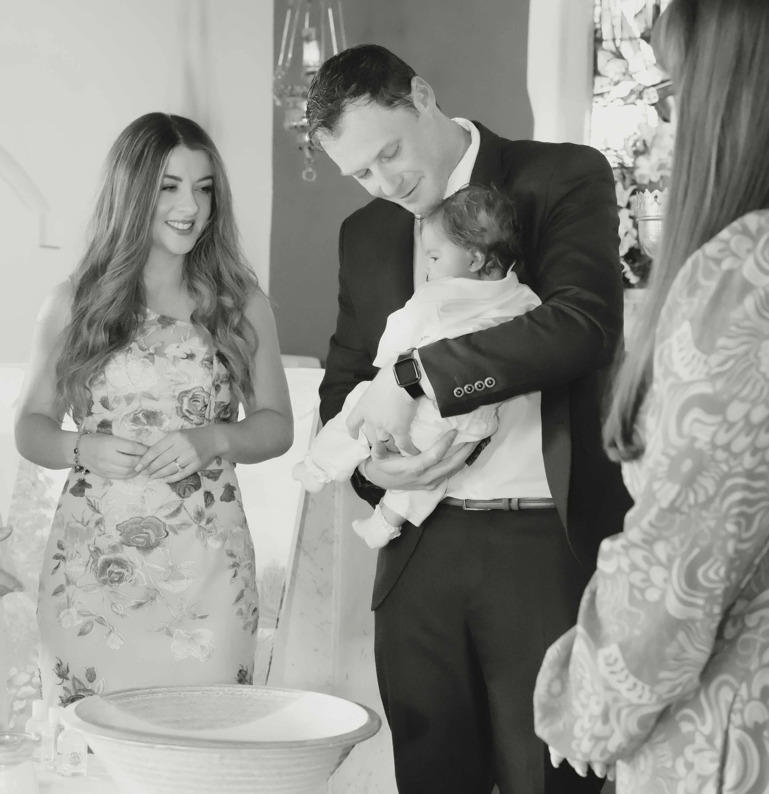 A man in a suit holding a baby during a christening ceremony in Ballyheigue, Co.Kerry.