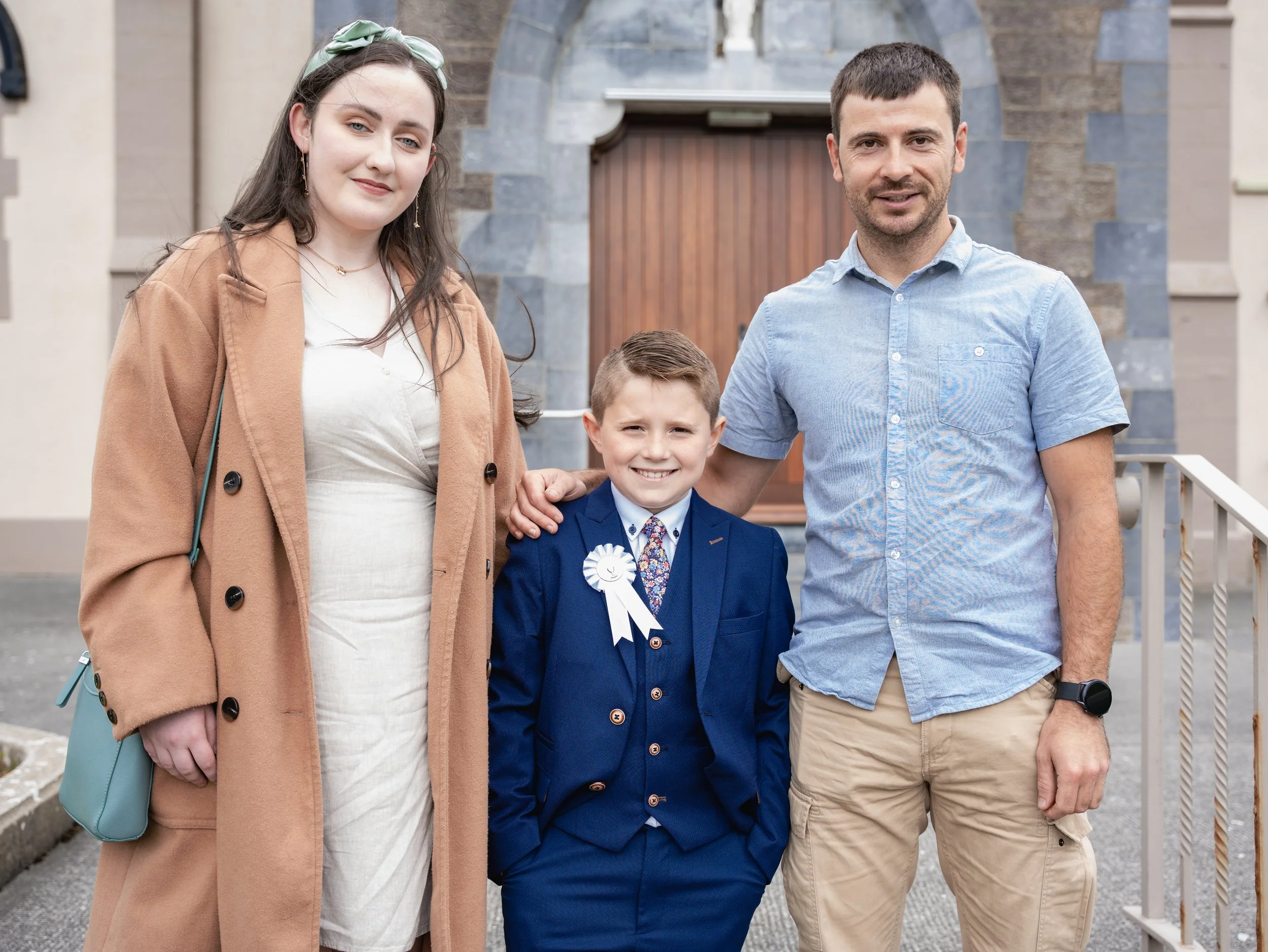 A photo of godparents standing near the child after first holy communion in front of church in Ballyheigue, Co.Kerry.