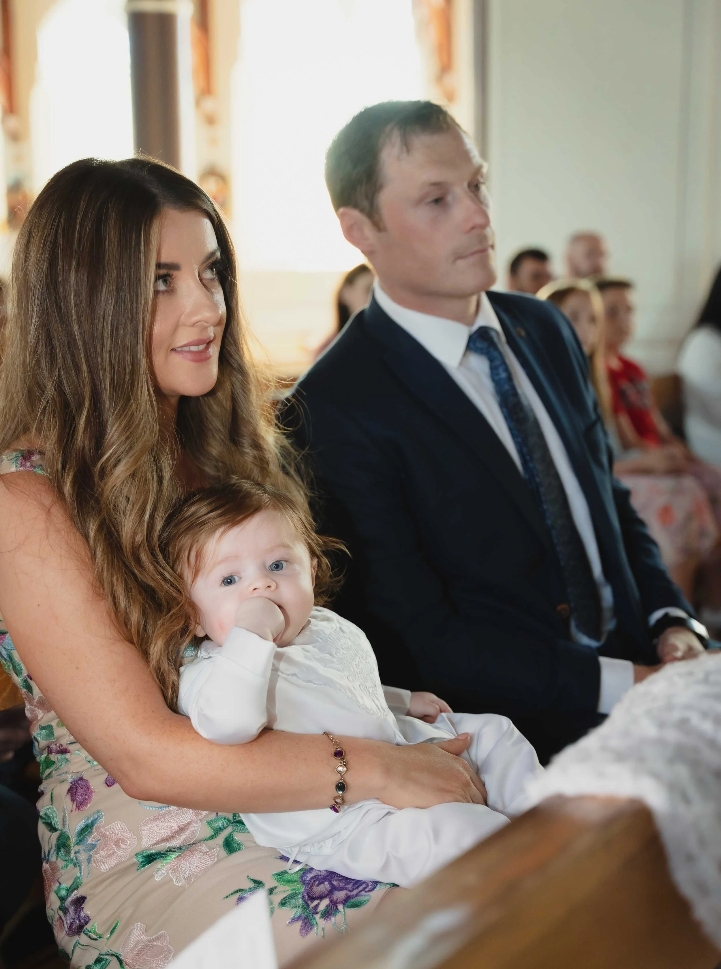 Photograph of a mother is sitting with a baby on her lap, during Chistening Ceremony in Ballyheigue, Co.Kerry