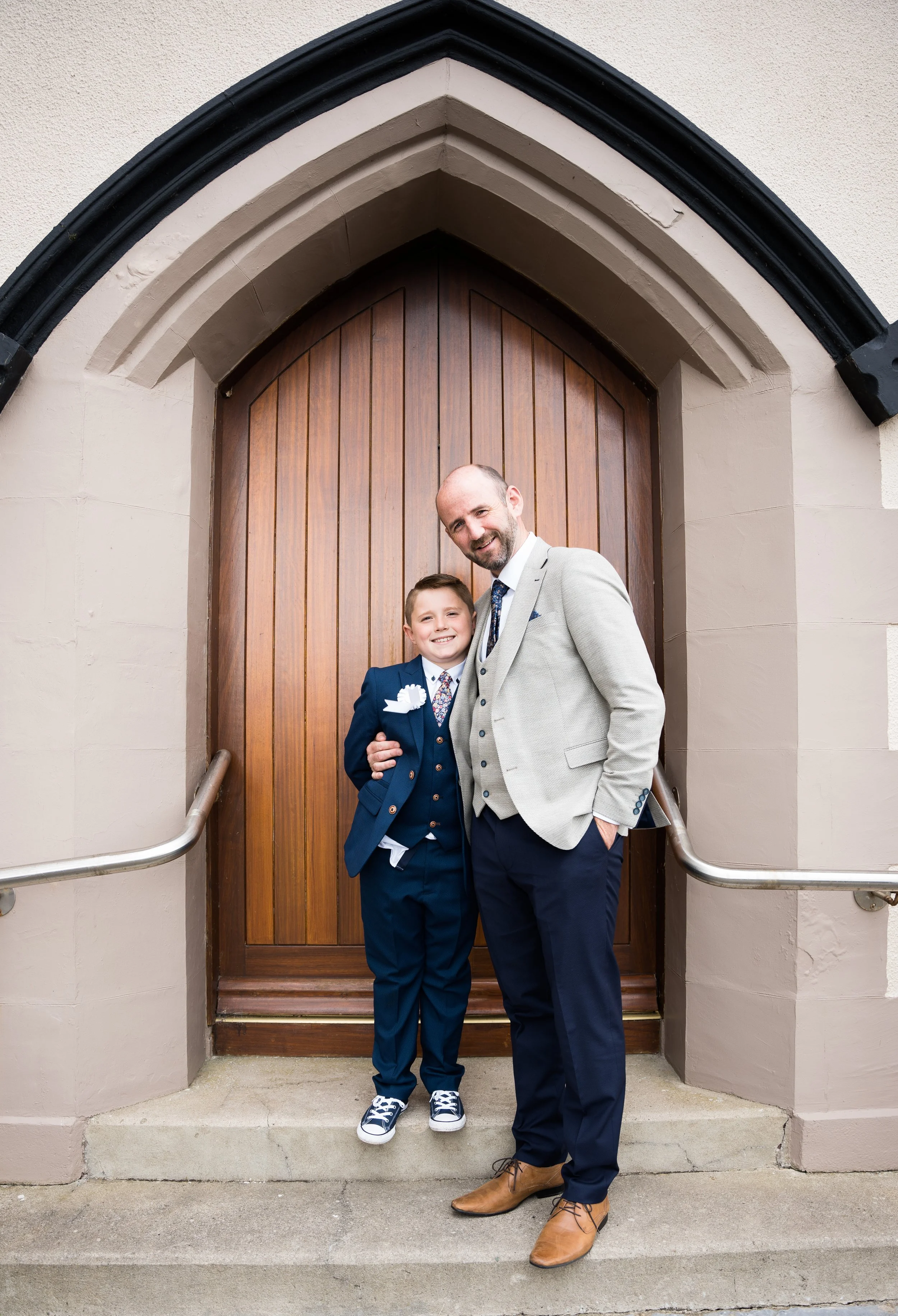 A portrait of a father and son standing together in front of a Ballyheigue Church , after boy's holy communion ceremony.
