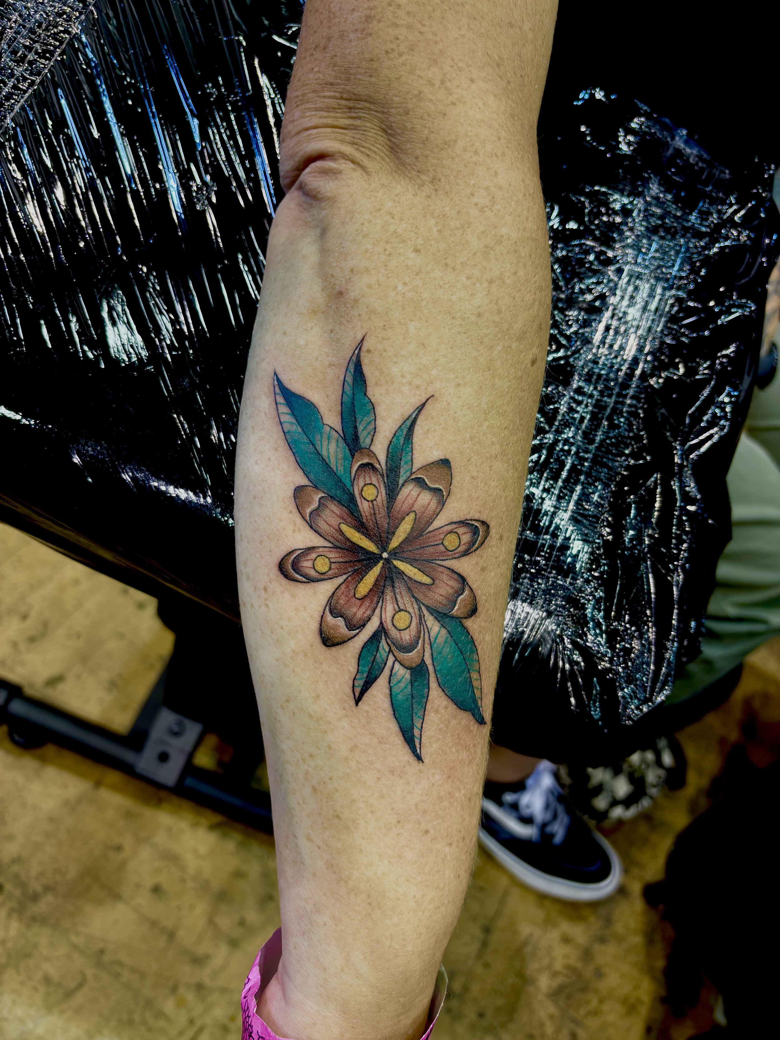 Colorful butterfly tattoo on person's forearm with blue and brown wings and yellow spots.