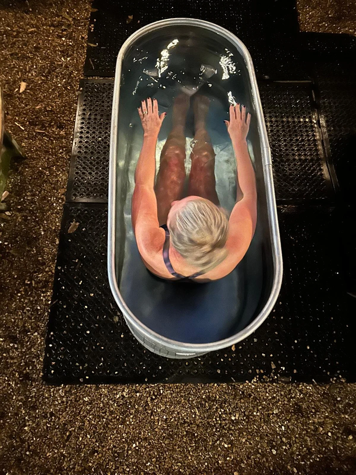 Person soaking legs in a foot bath or hot tub, viewed from above.