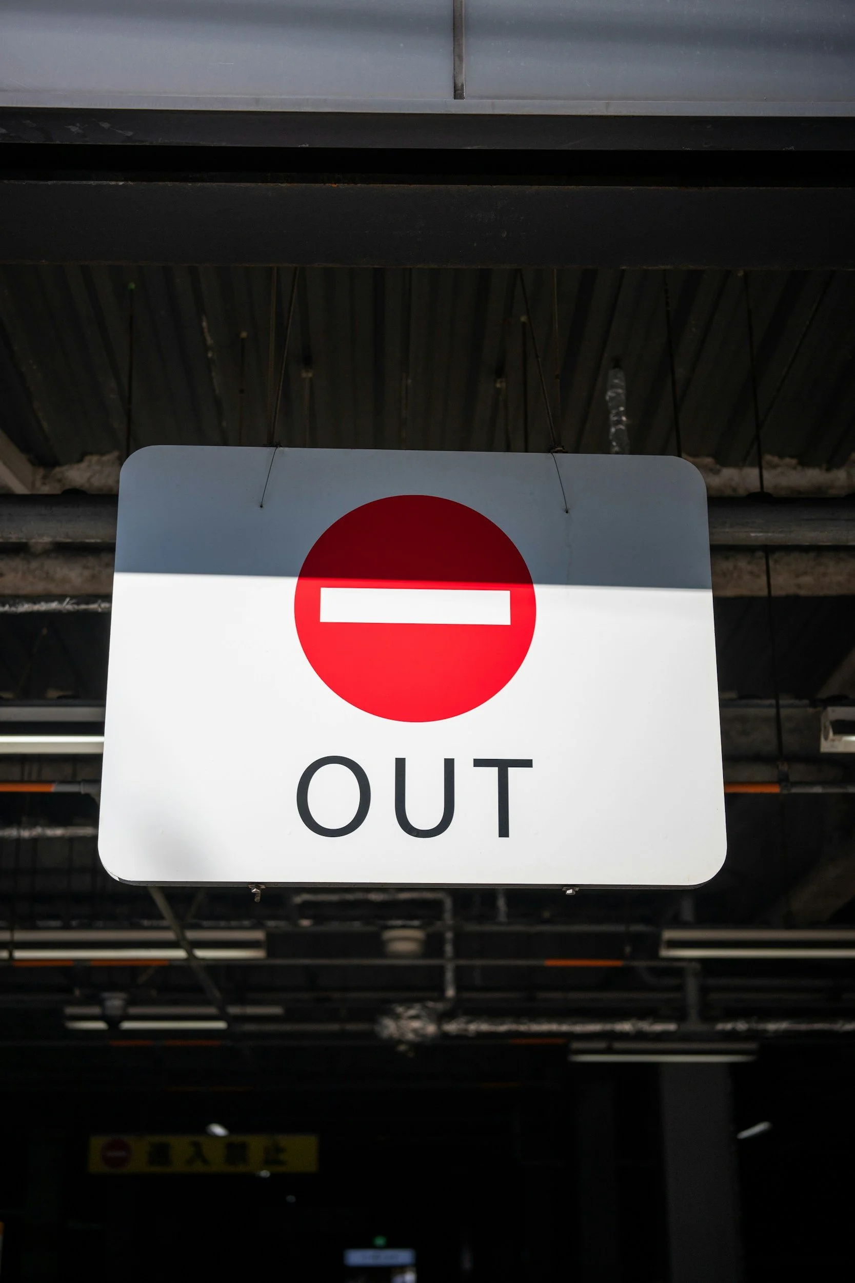 A white sign with a red circle and a white horizontal line indicating no entry, with the word 'OUT' underneath.