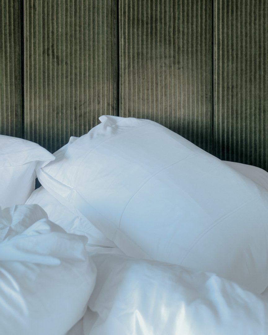 Minimalist bedroom detail with white pillow and textured green olive wall finish