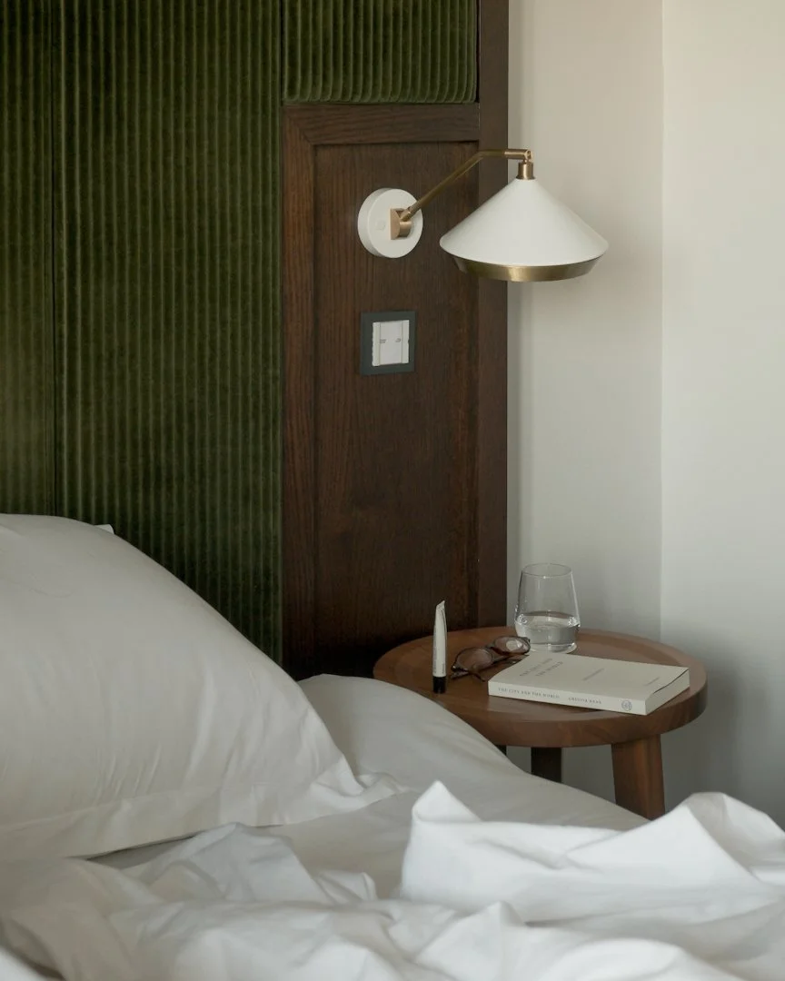 Modern bedroom design with gold wall lamp, wooden headboard, and styled bedside table