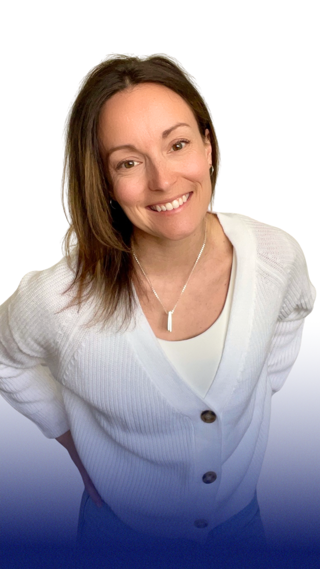 A woman with shoulder-length brown hair smiling at the camera, wearing a white cardigan, a white top, a silver necklace with a vertical pendant, and earrings, against a white background.