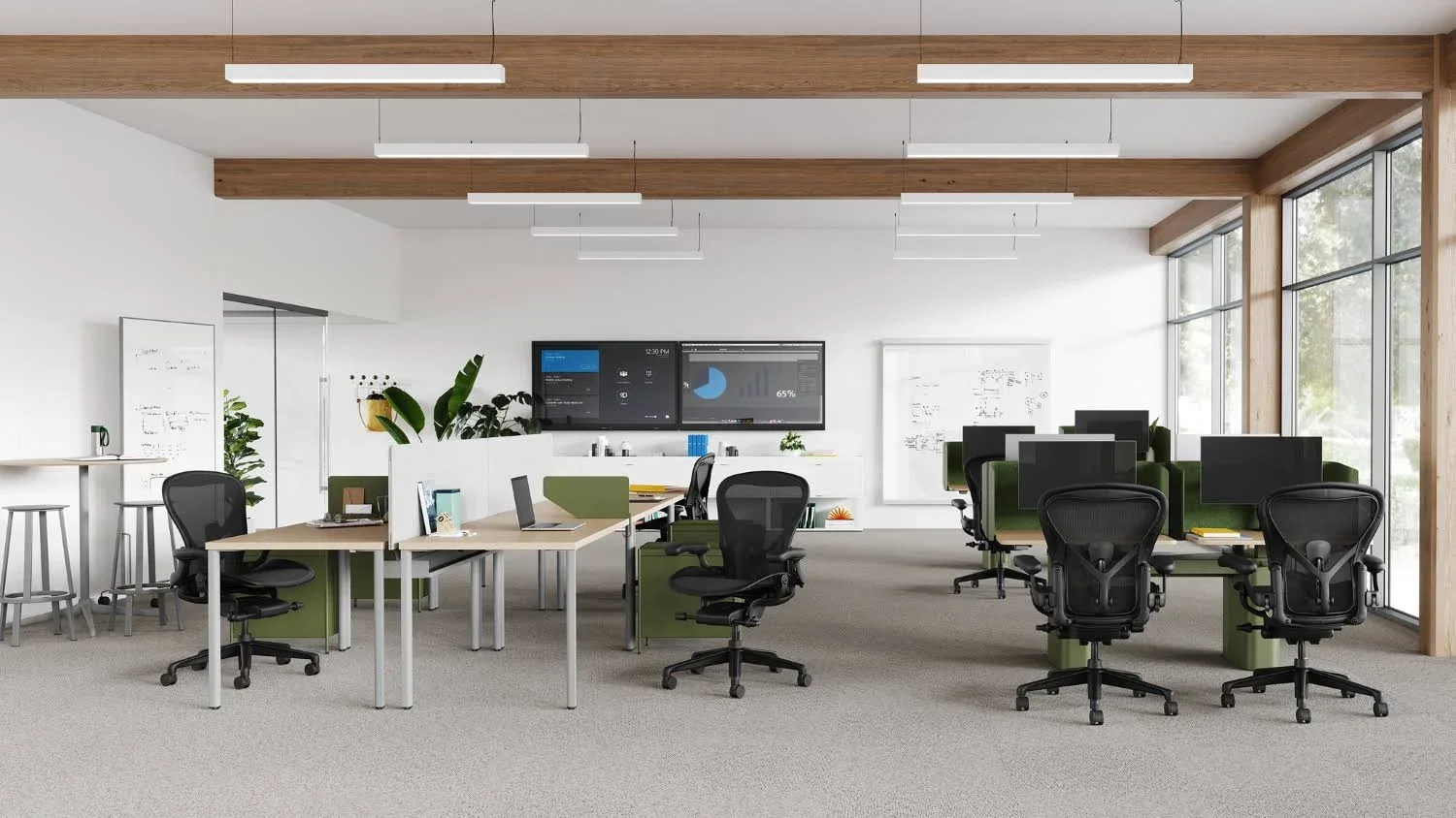 Modern office space with desks, office chairs, large windows, whiteboards, and digital displays, decorated with plants.