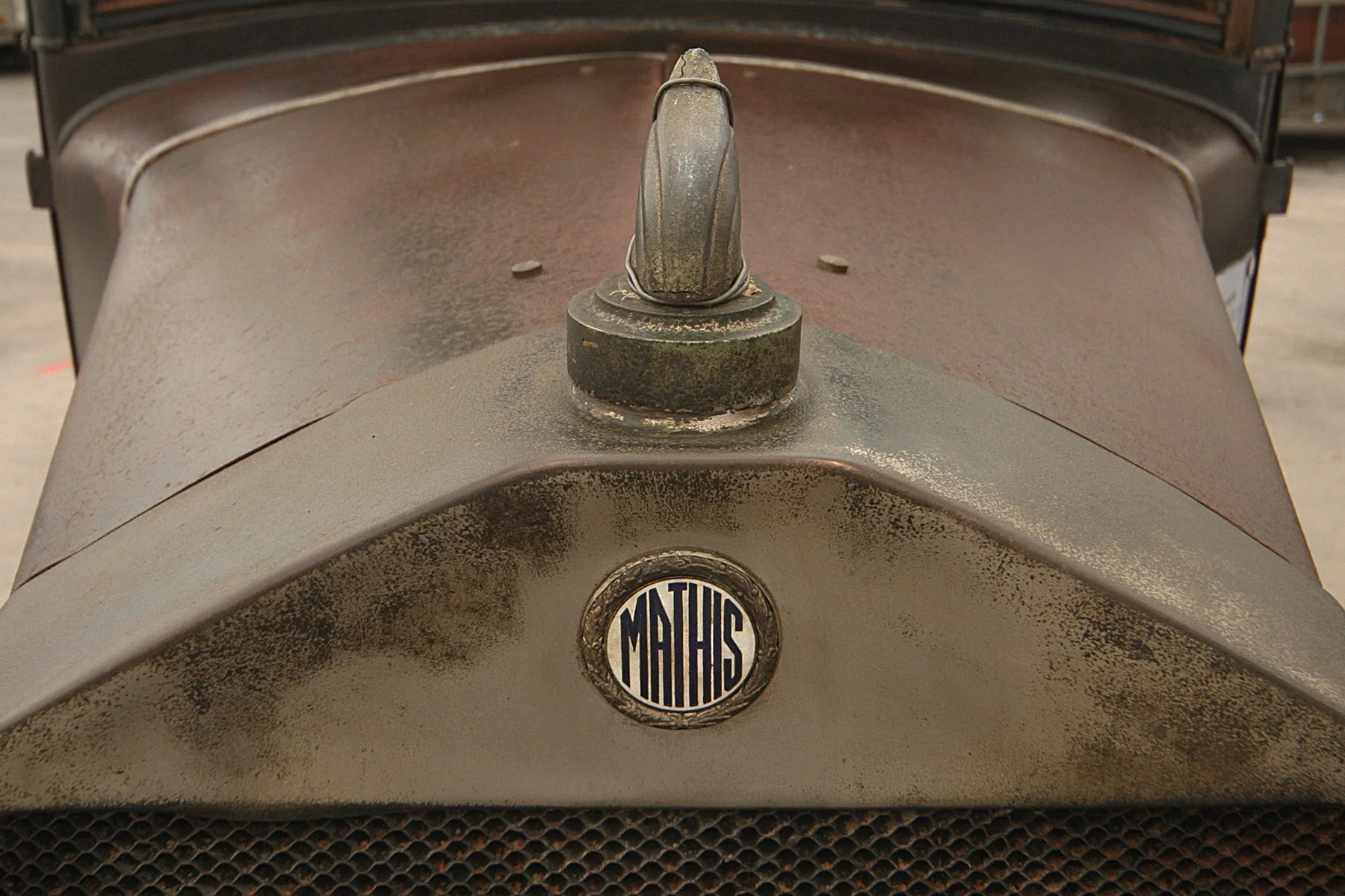 Vue de l'avant d'une vieille voiture, mettant en évidence le capot et le badge "Mathis".