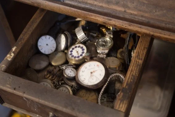 Un tiroir en bois rempli de montres et de horloges anciennes.