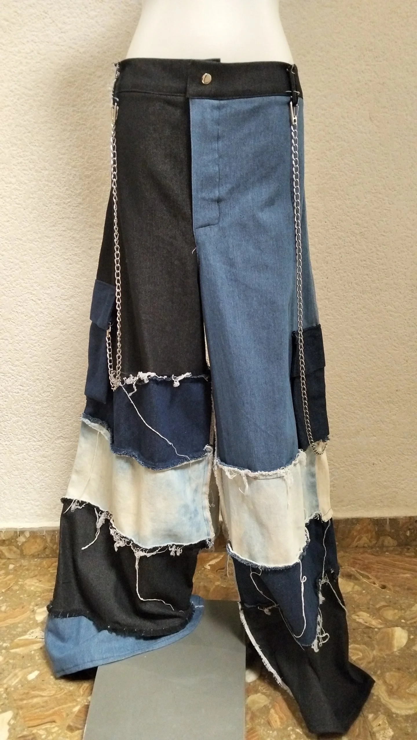 Pantalones largos de mezclilla de diferentes tonos y costuras deshilachadas.