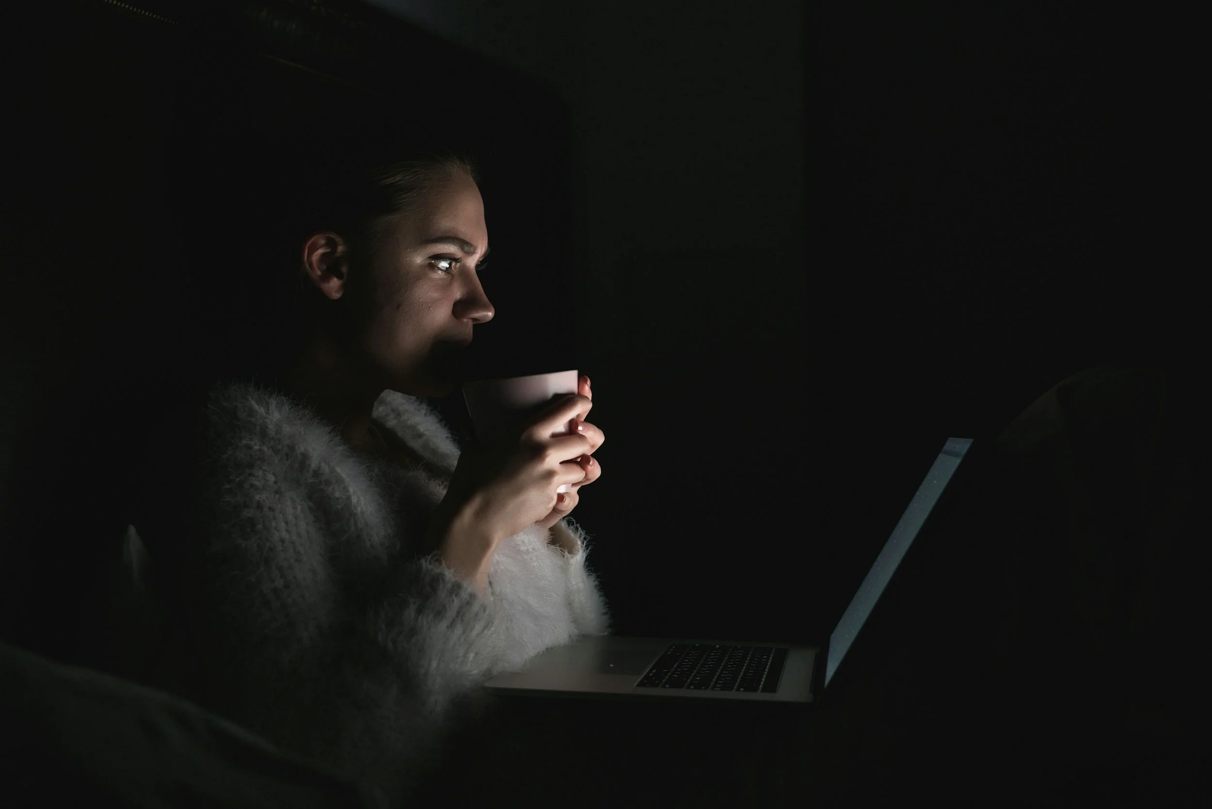 Woman with laptop in dark room
