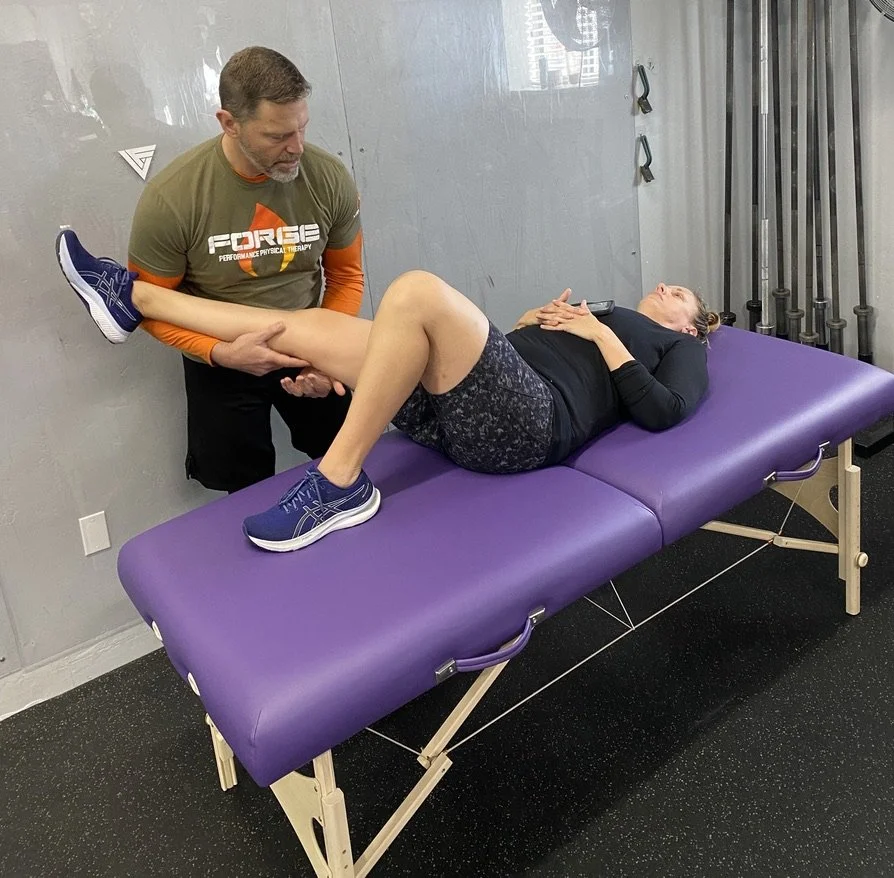 Physical therapist assisting a woman with leg exercises on a purple therapy table in a rehab clinic.