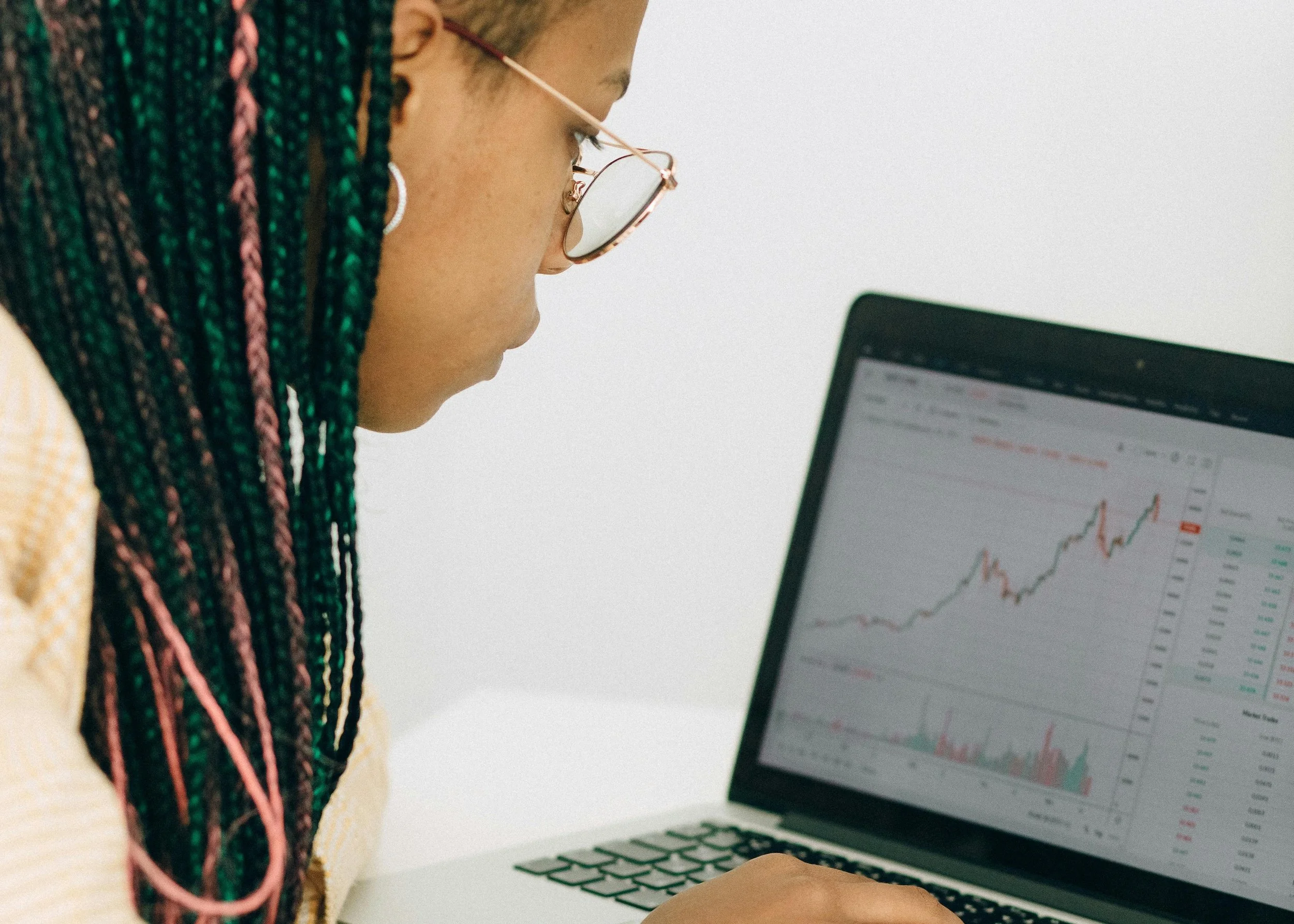 A young Black female leader works on her computer, analyzing a growth chart showing an upward trend