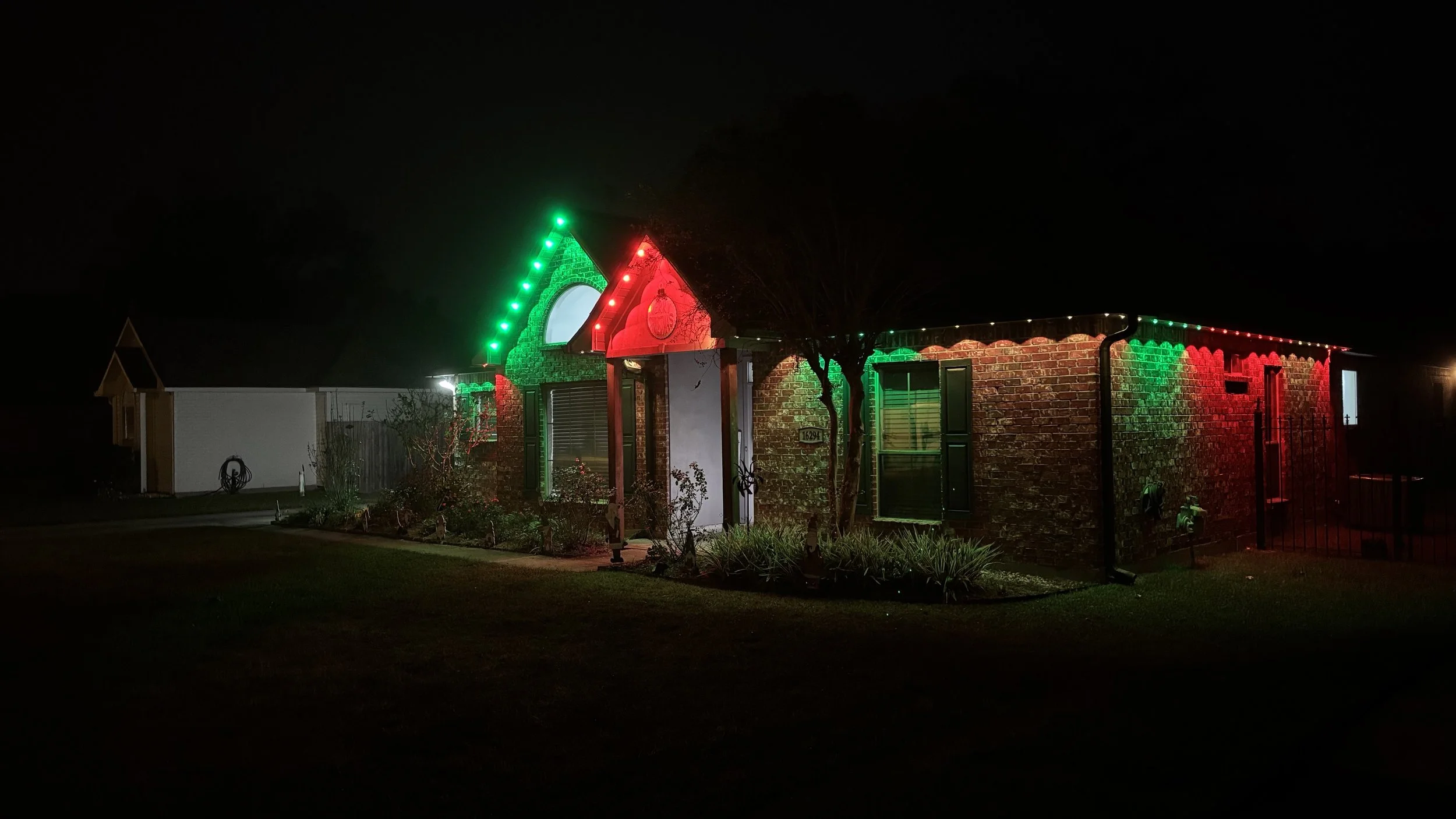 A house decorated with Christmas lights in red, green, and white colors at night.