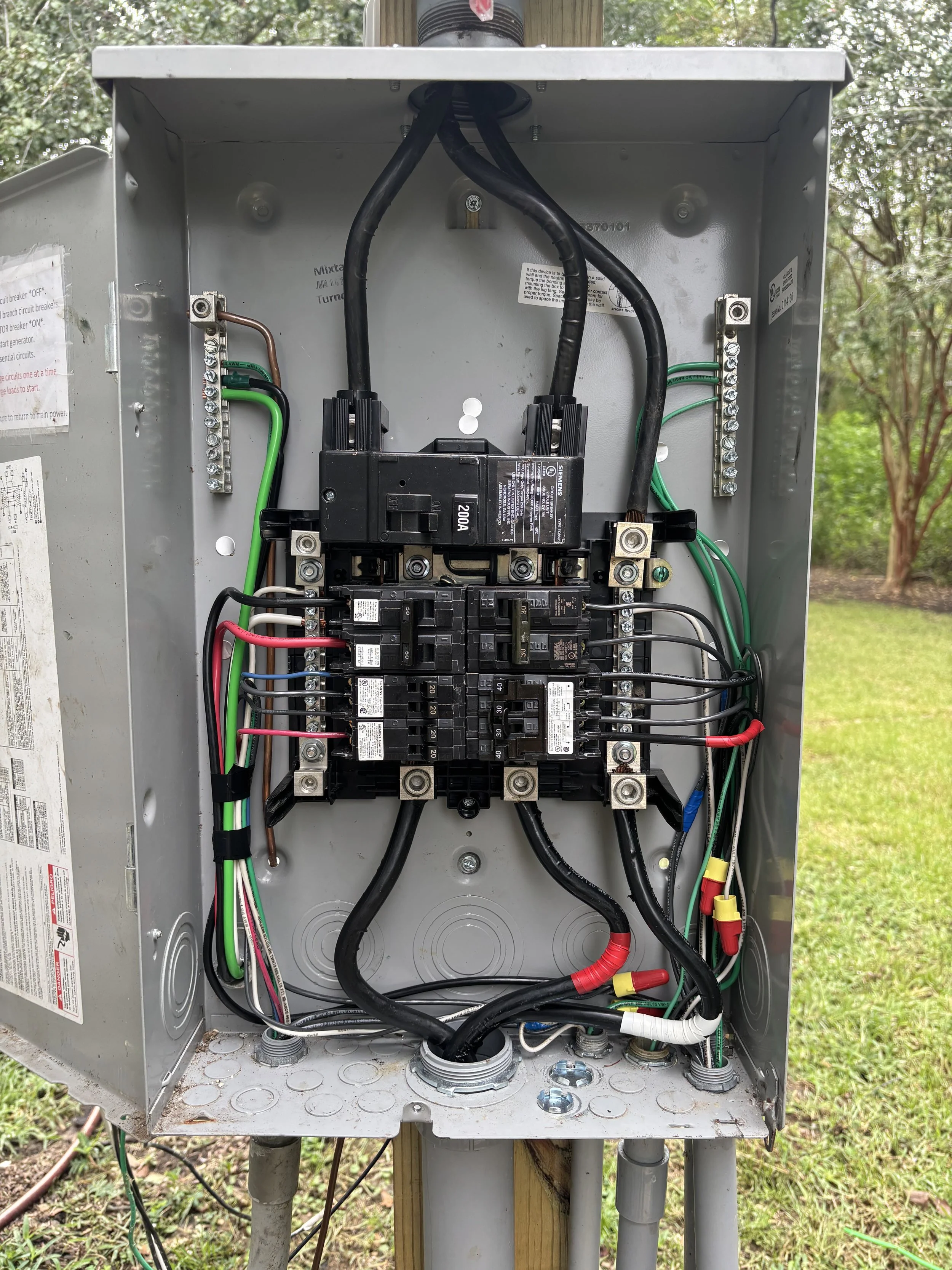Open electrical service panel with circuit breakers, wiring, and grounding connections.