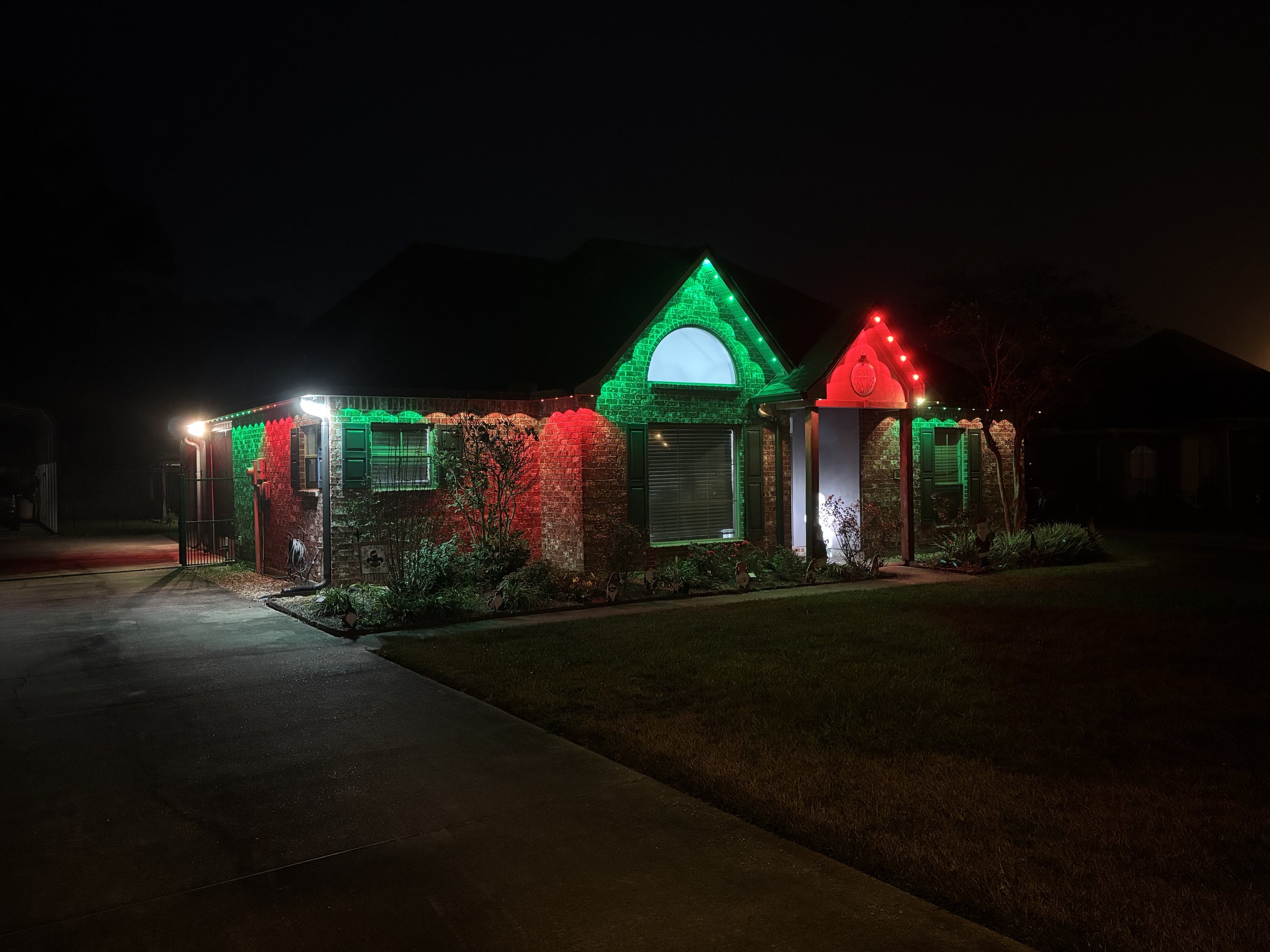 A house decorated with Christmas lights at night, featuring red and green lights outlining the structure.