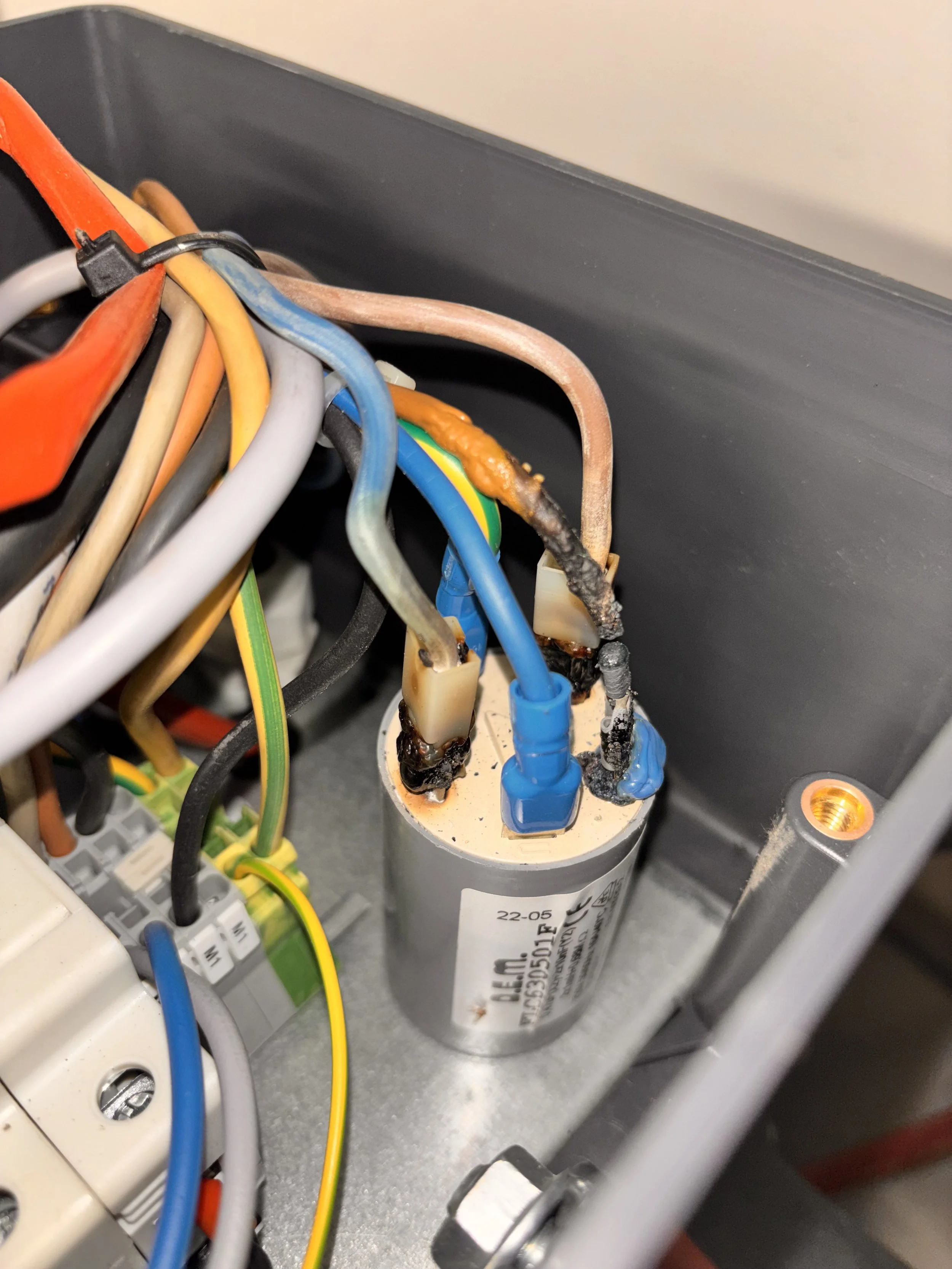 Electrical wiring and components inside an electrical panel or device, with some wires burned or melted.