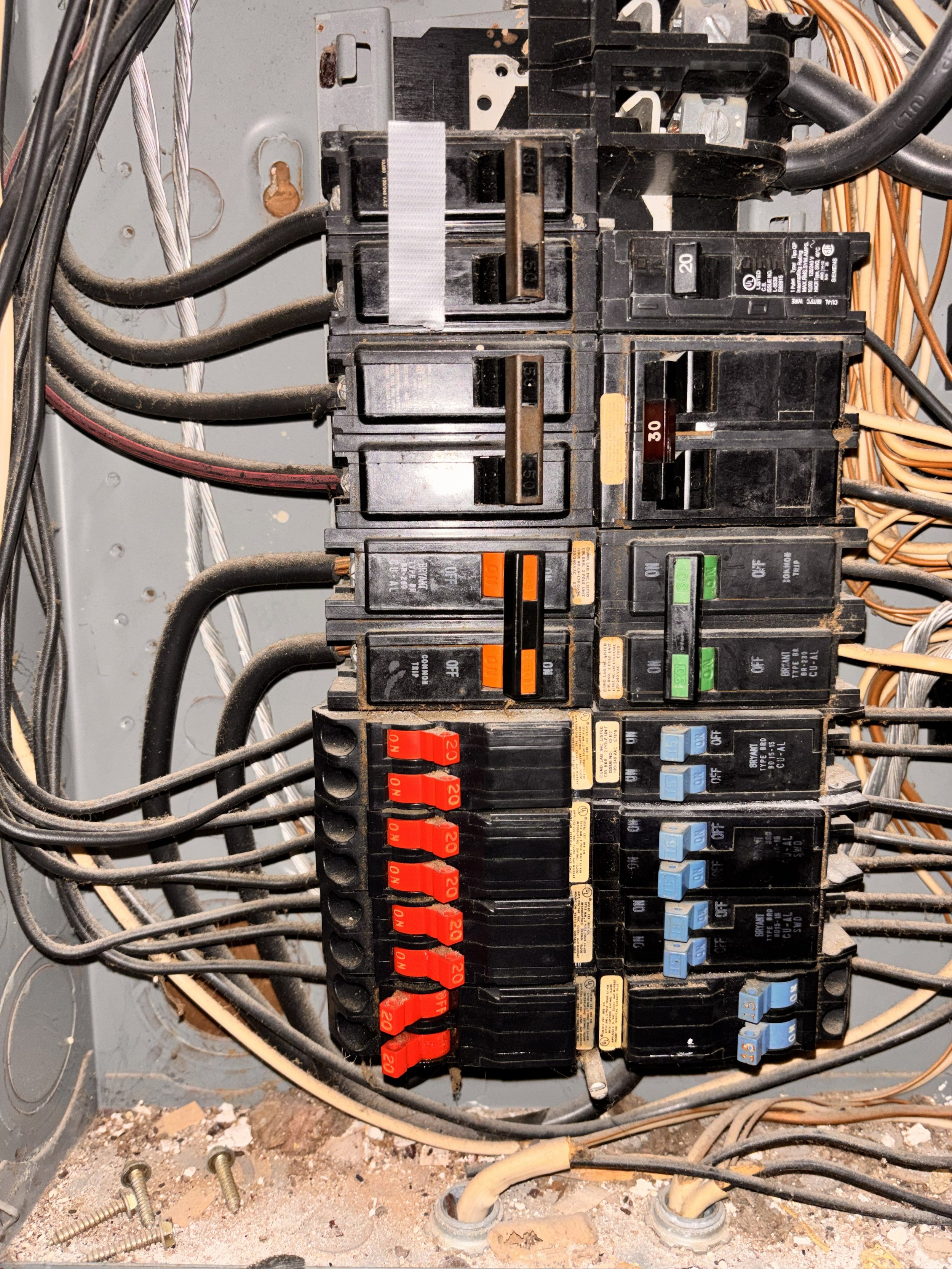 Close-up of an electrical breaker panel with various switches, wires, and circuit breakers in different sizes and colors.