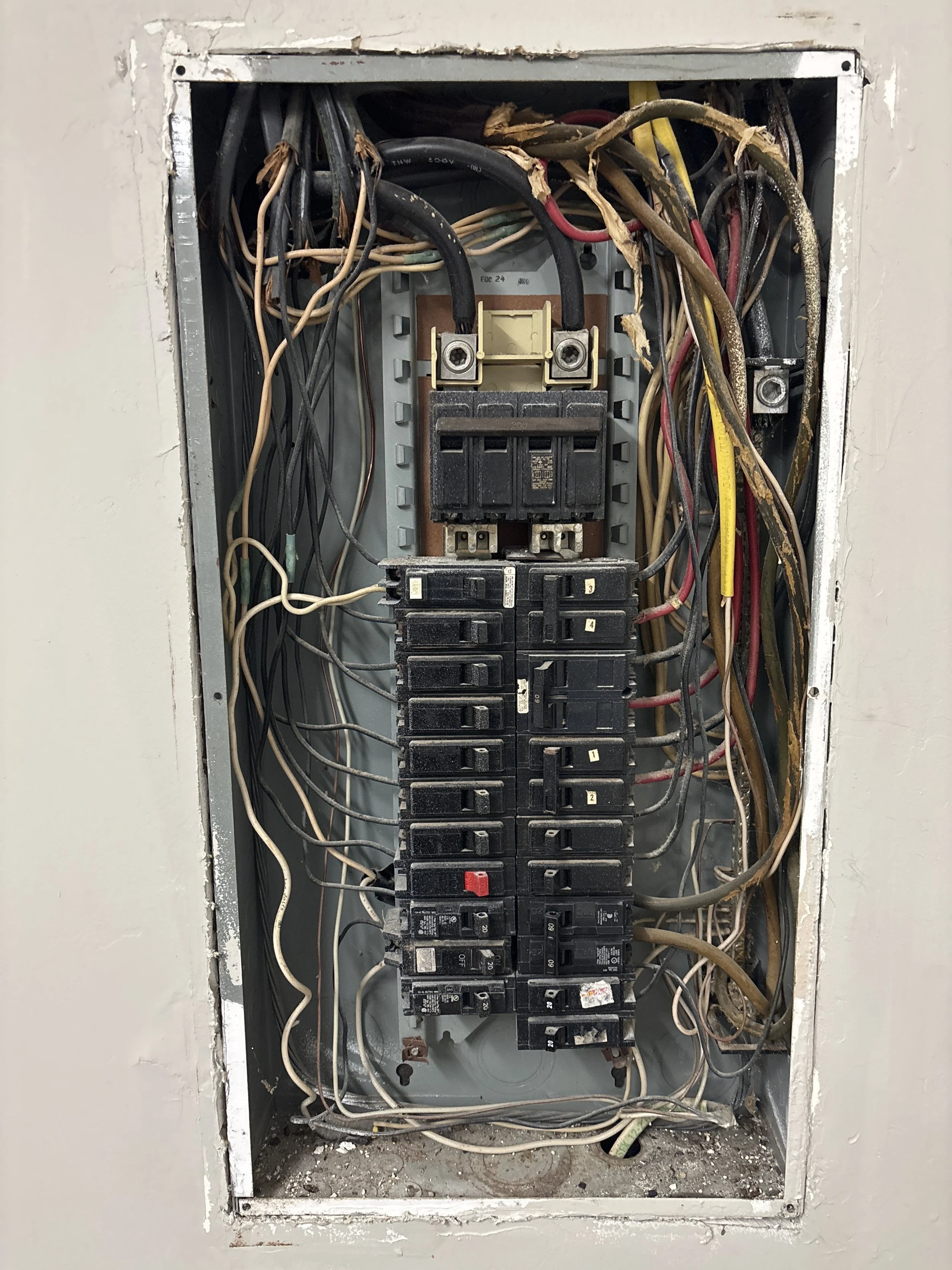 An electrical panel with various wires and circuit breakers inside.
