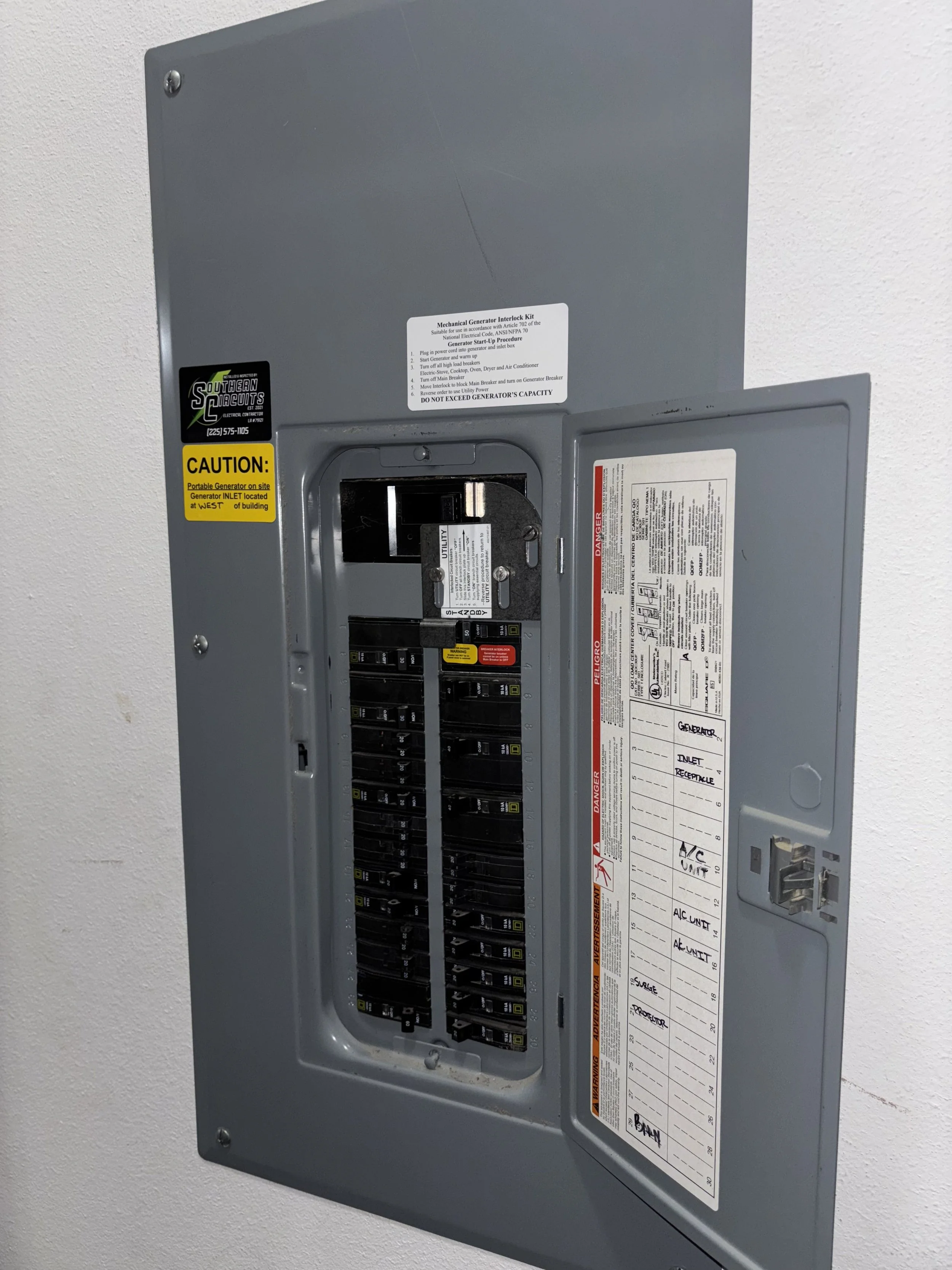 Electrical breaker panel with open door on a white wall.