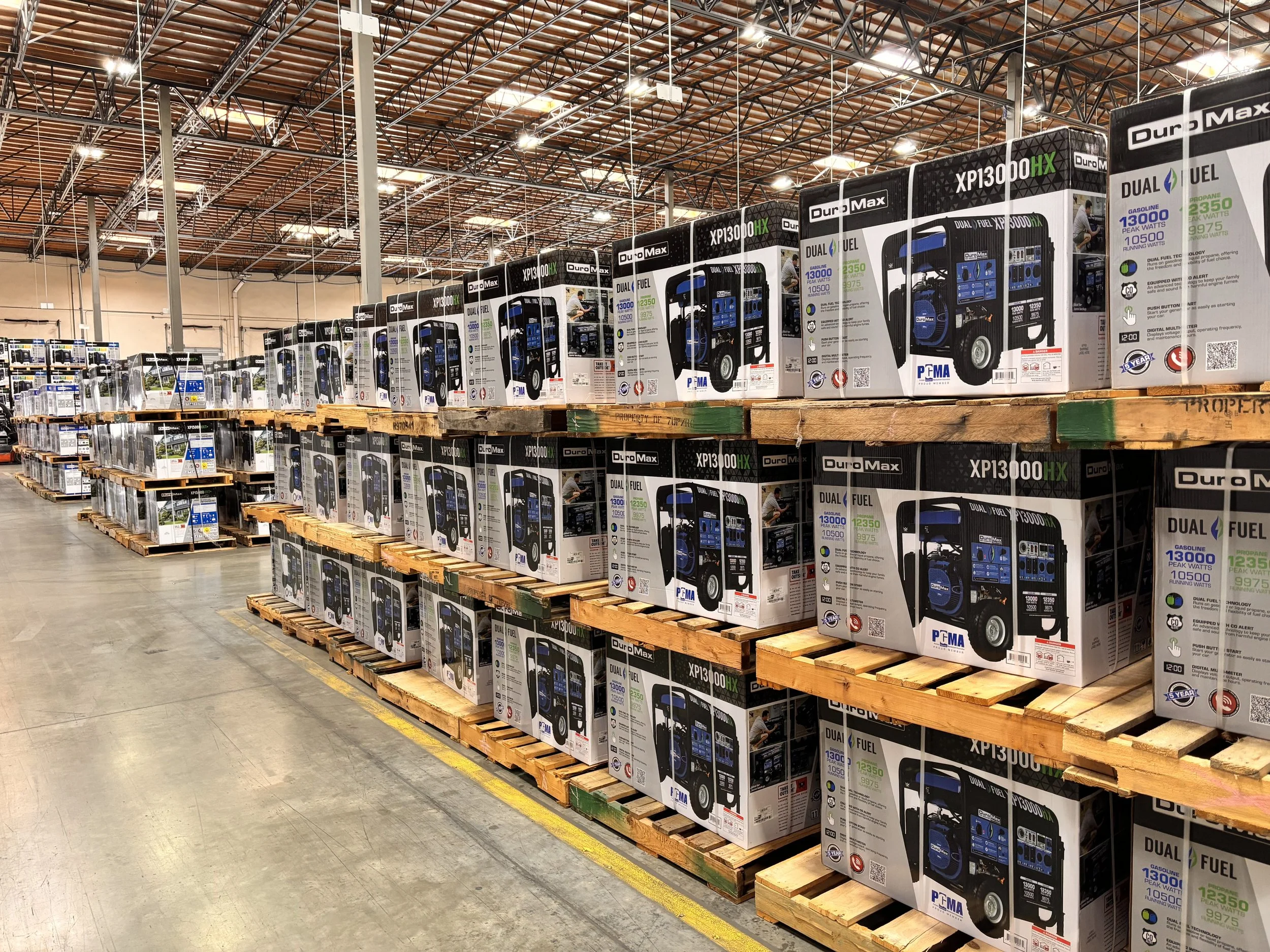 Rows of portable generators in boxes on pallets in a warehouse.