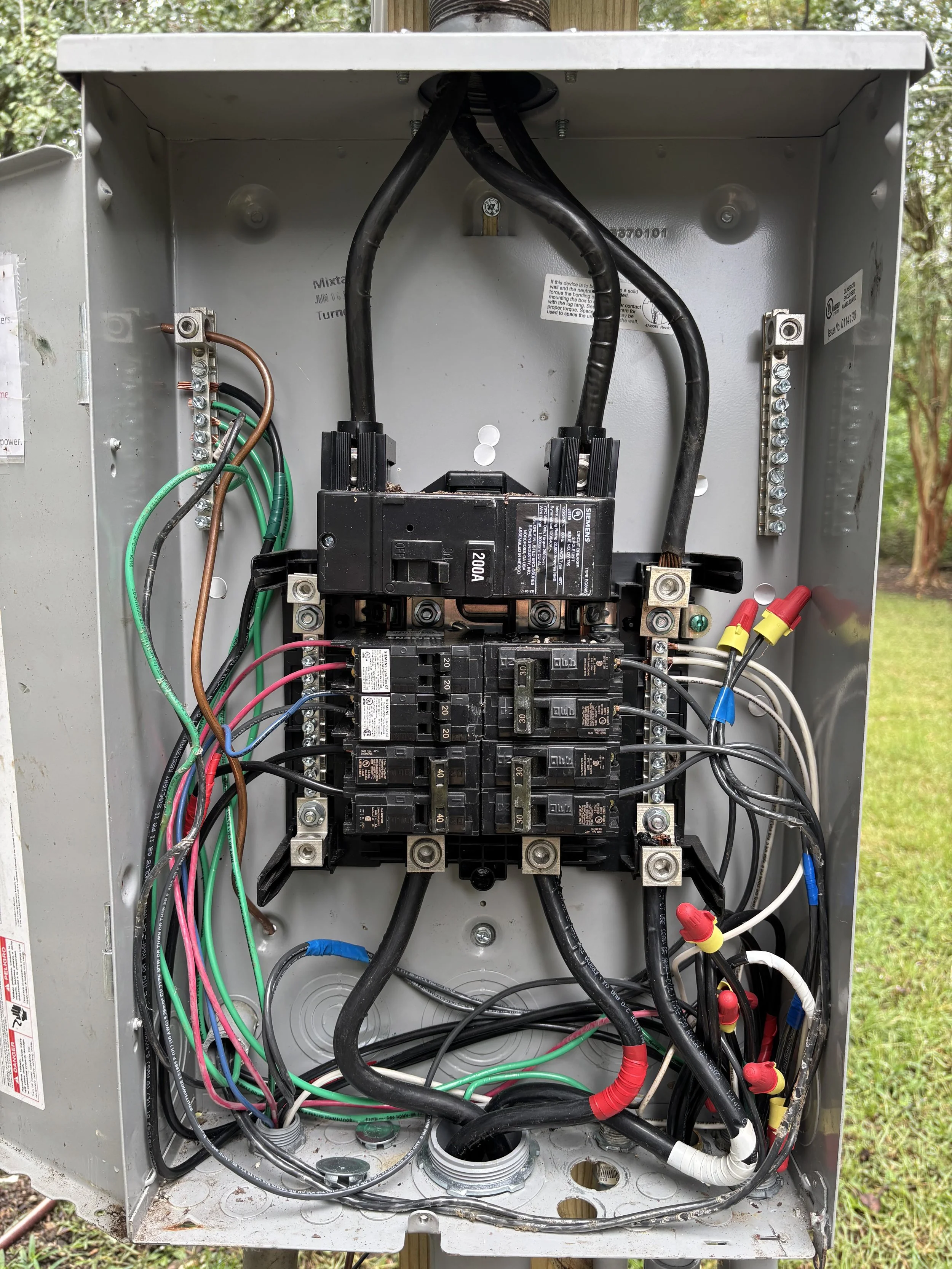 Interior of an electrical panel with multiple wires, circuit breakers, and wiring connections.
