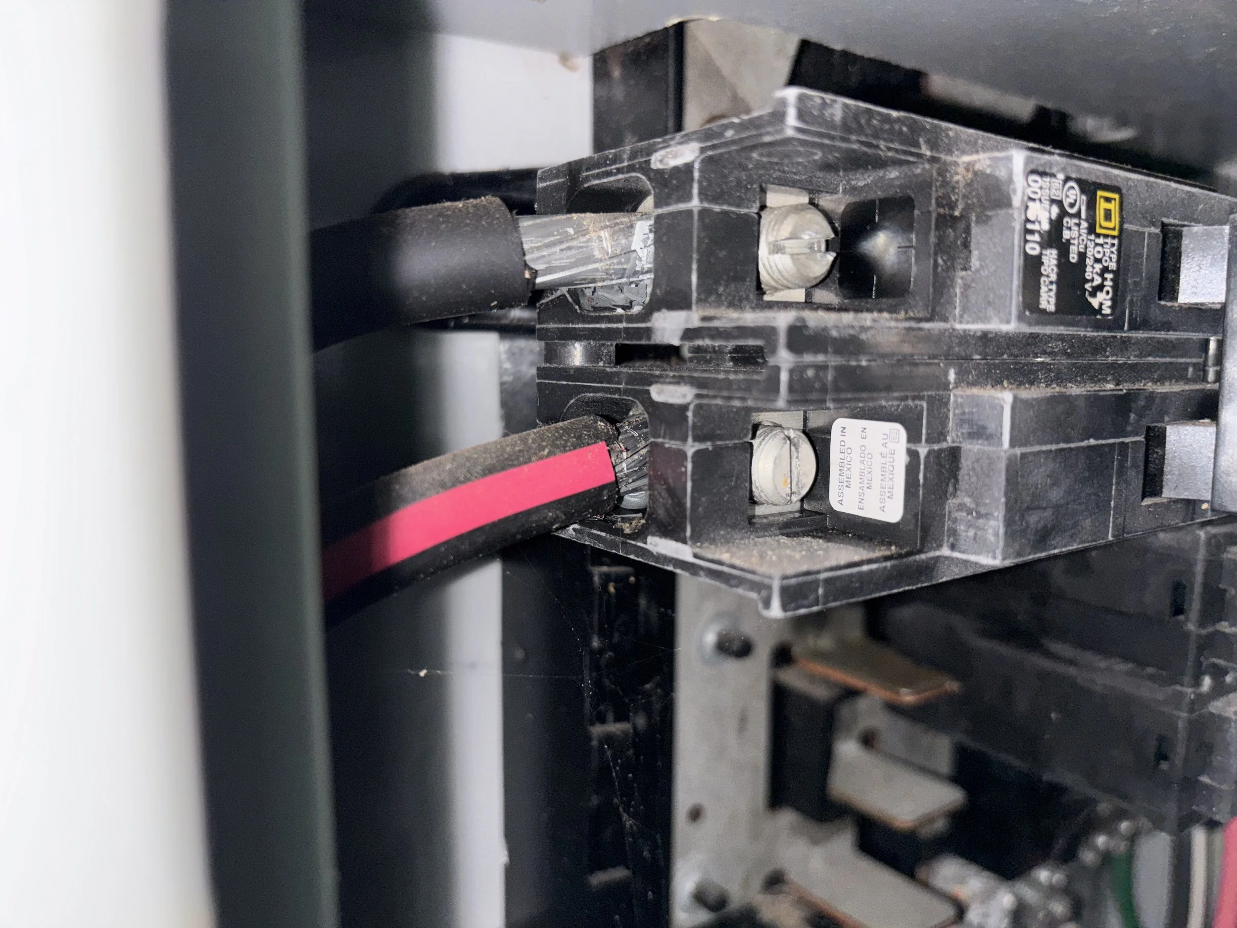 Close-up of an industrial circuit breaker with black, gray, and pink wires connected.