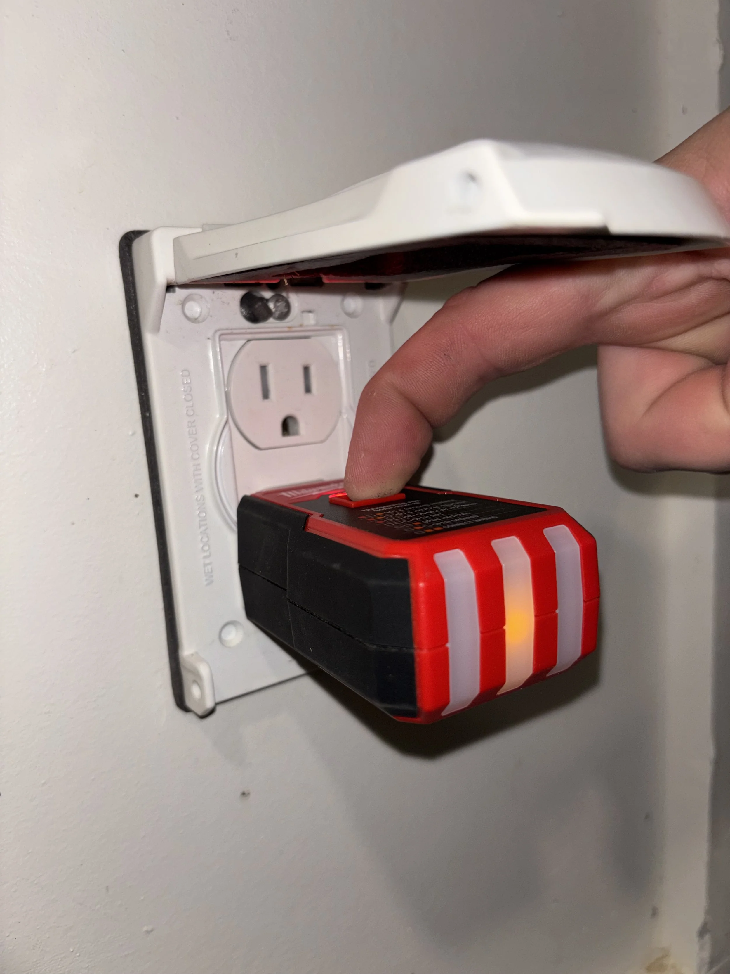 Person plugging a red and black rechargeable power tool into an electrical outlet.
