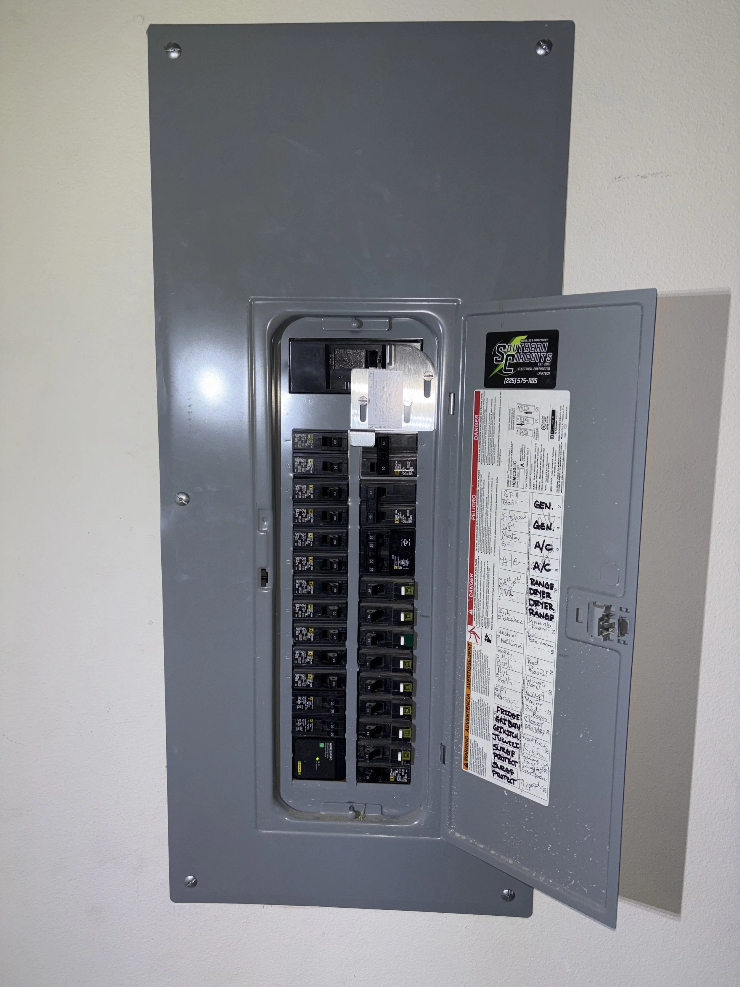 Electrical breaker box with open door, showing circuit breakers inside, mounted on a wall.