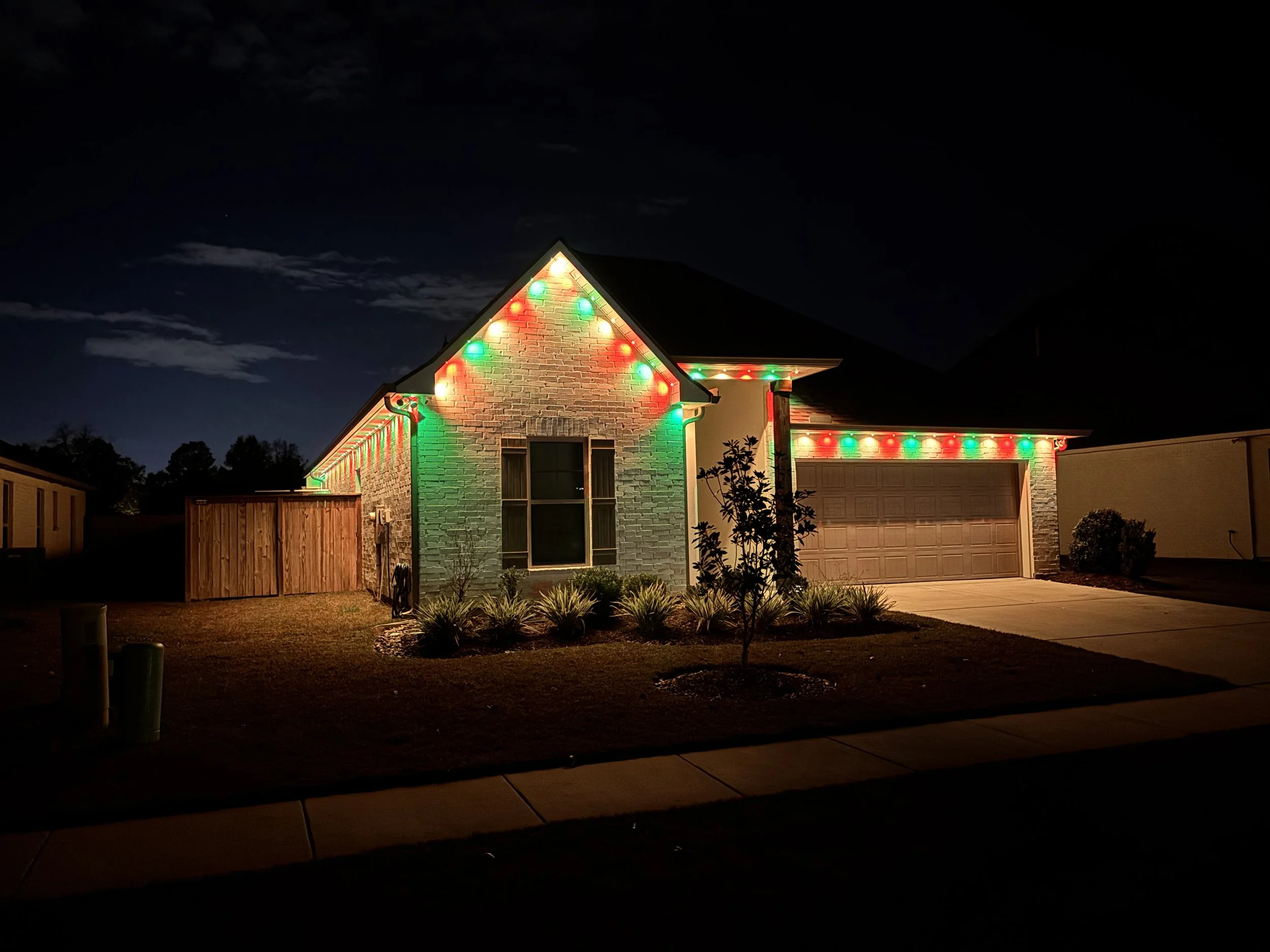 A house decorated with red and green Christmas lights at night.