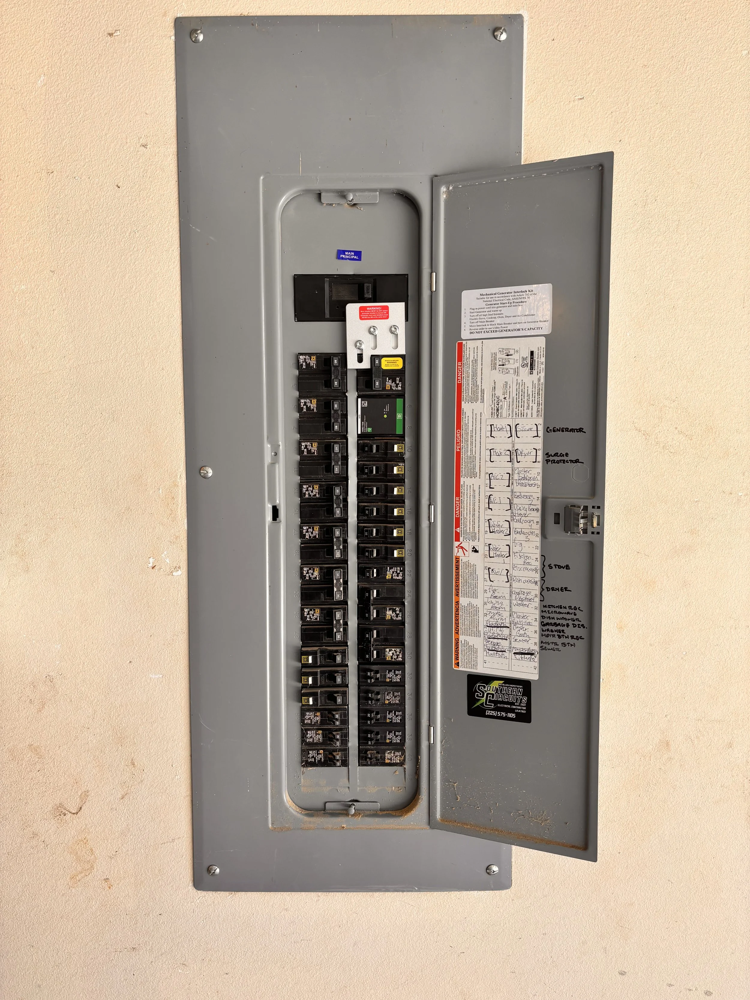 Open electrical breaker panel with multiple circuit breakers mounted on a wall.