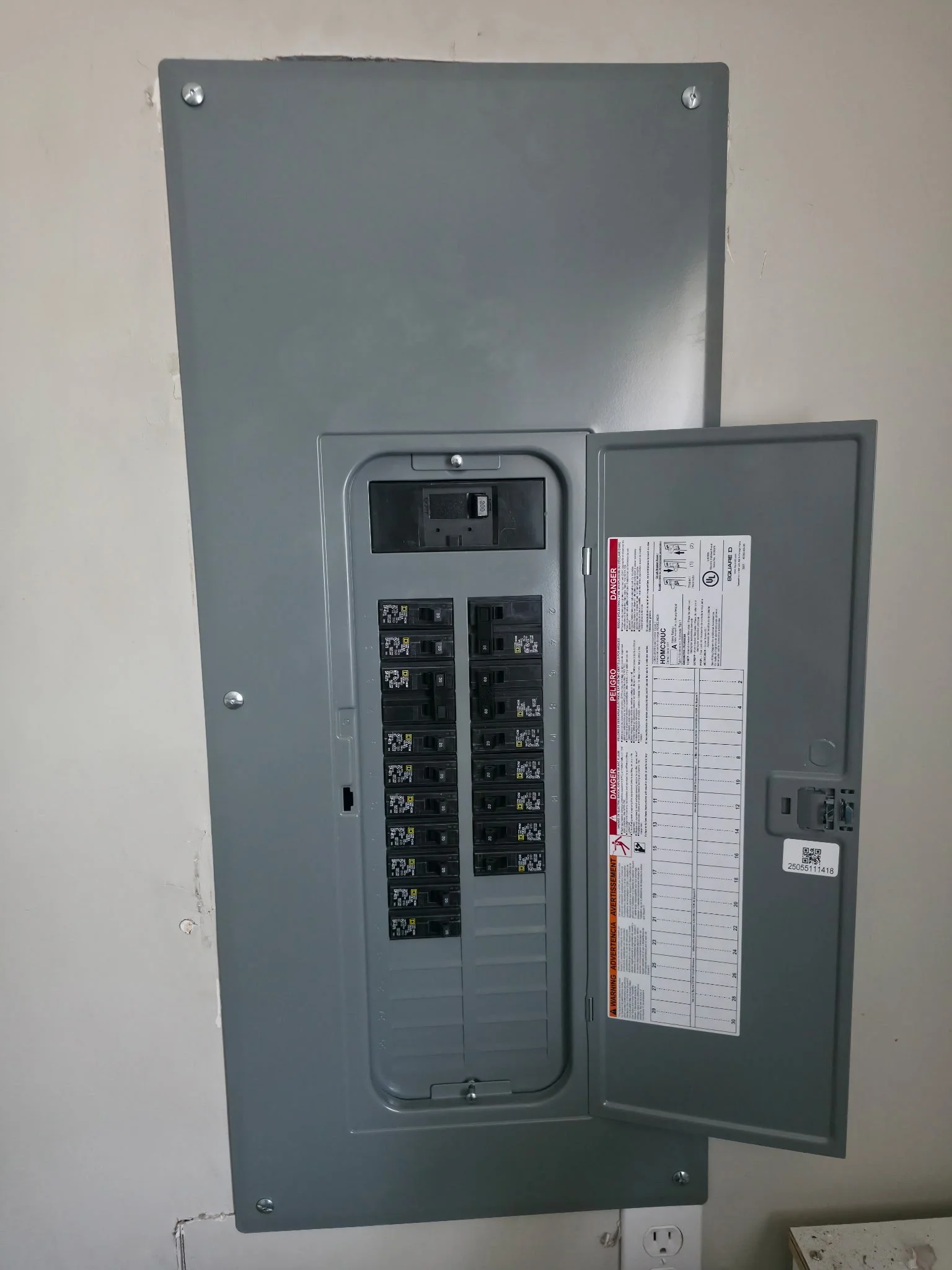 Electrical breaker box with open door showing circuit breakers inside.