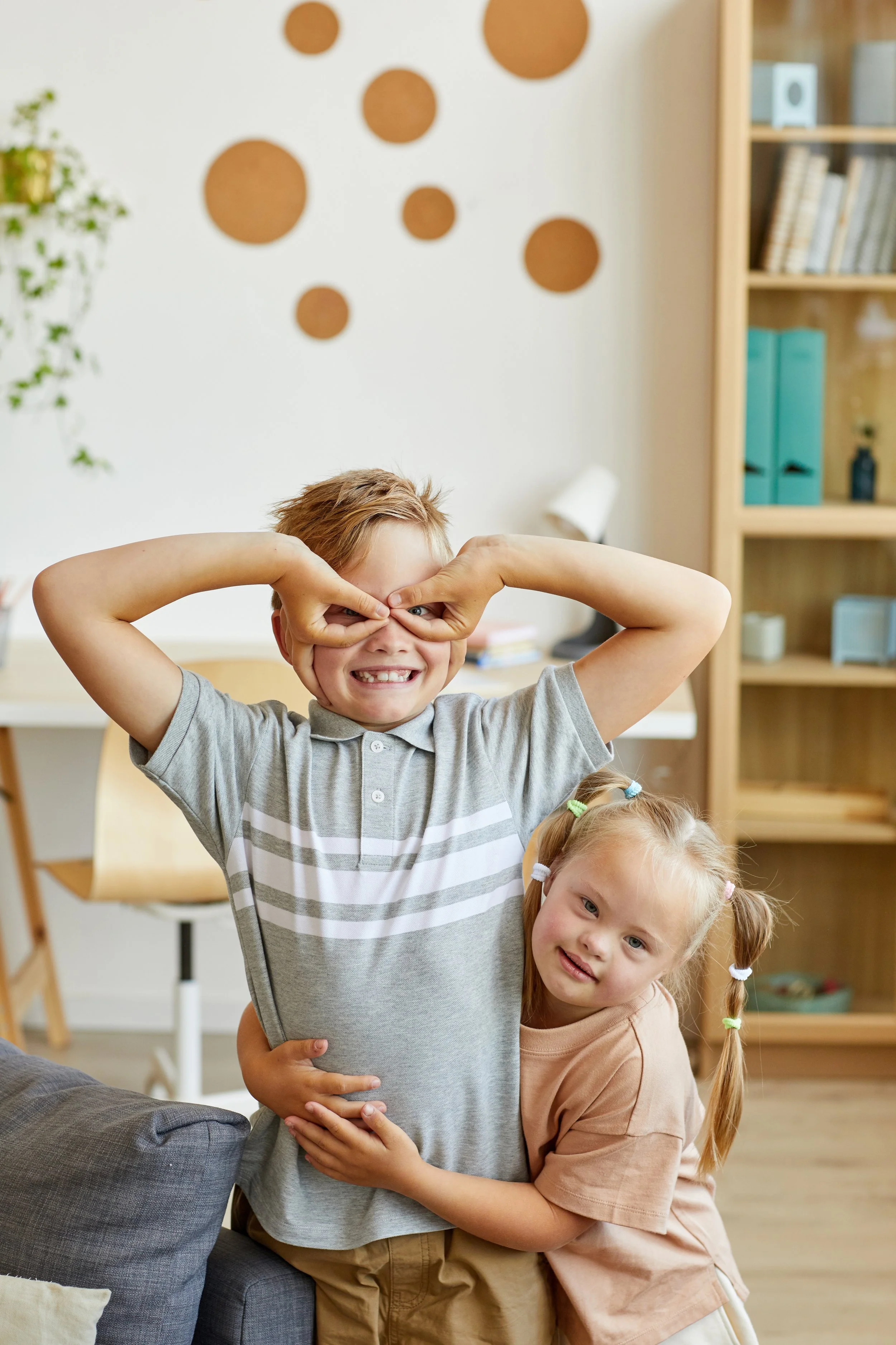 two young white children, a young boy making funny faces and a young girl giving him a hug.
