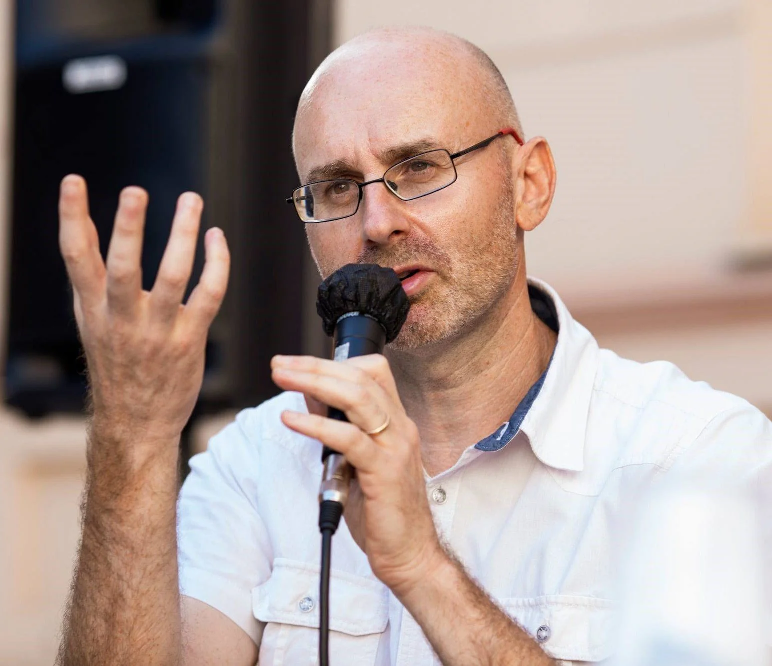 A picture of Fraser, a white man, during a speech holding a microphone.