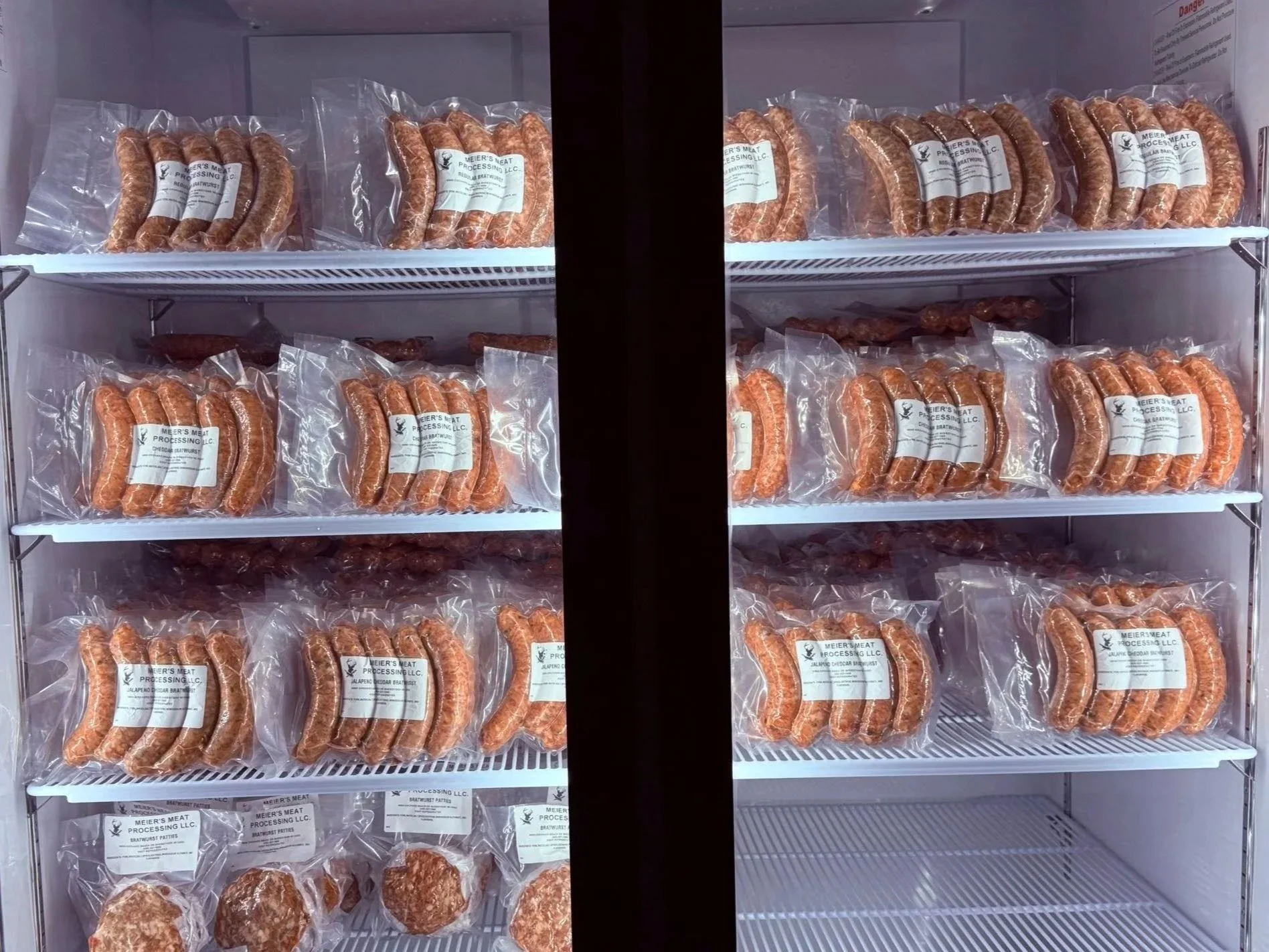 Sausages packages on shelves inside a refrigerator.