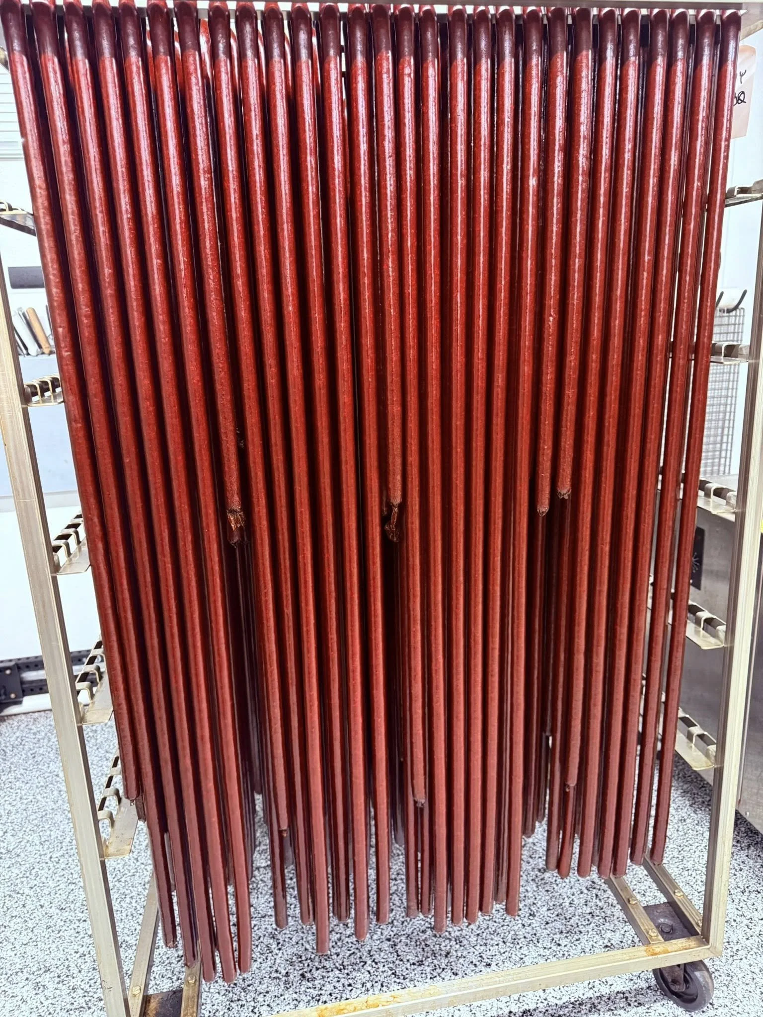 A display of multiple red golf clubs stored upright on a metal cart.