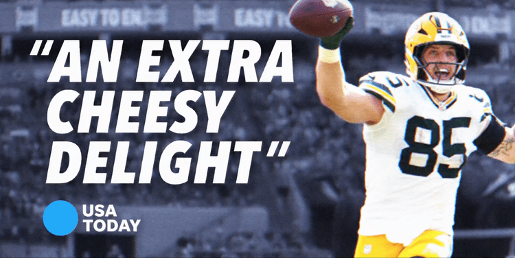 Football player in a white and yellow uniform celebrating with arms raised, holding a football.