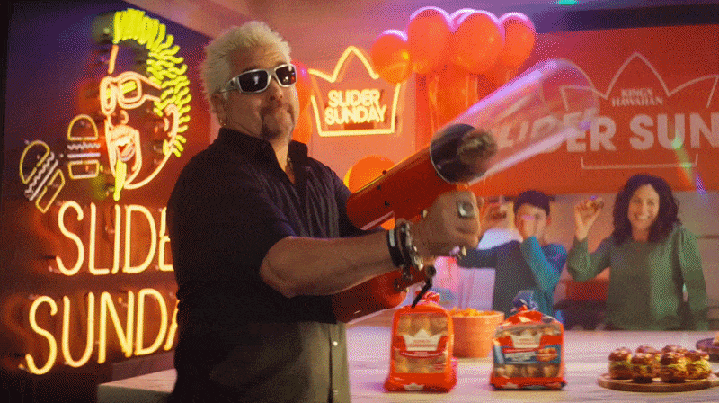 Guy Fieri using a cannon to shoot a slider into the mouth of an excited dad.