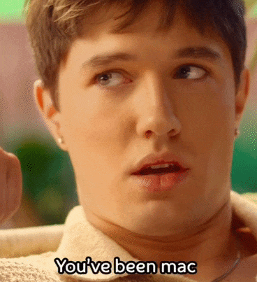 Close-up of a young man with short brown hair in a tropical setting. He's on the set of a dating reality tv show. The subtitles at the bottom reac, "You've been mac and cheated babe."