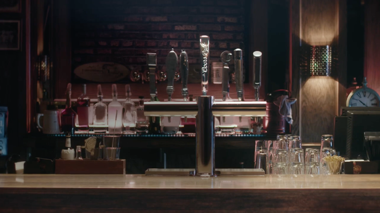 Bar with multiple beer taps, glasses, and bar tools behind the counter.