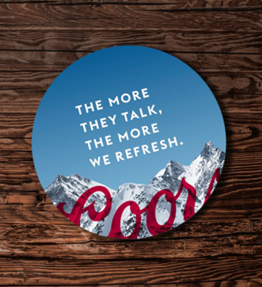 Circular sticker with a mountain landscape background and the text "The more they talk, the more we refresh."